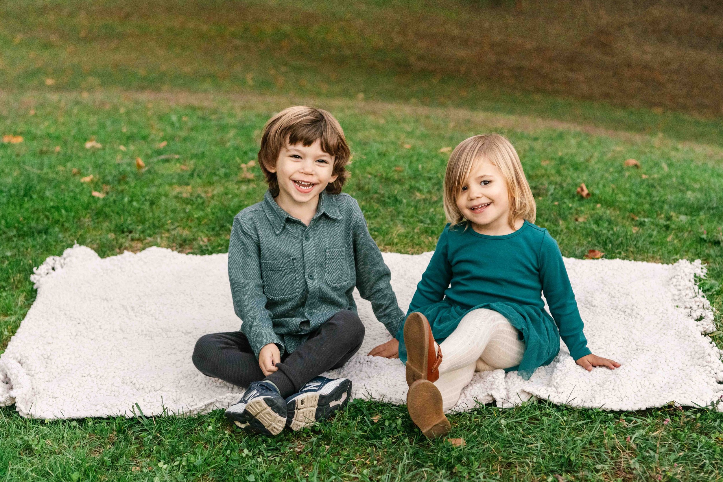  A brother and sister sitting on a blanket in a grass park in New York by Nicole Hawkins Photography. brother and sister picnic portrait sitting on a blanket #NicoleHawkinsPhotography #NicoleHawkinsFamilies #NJphotographers #familyphotos #CentralPark