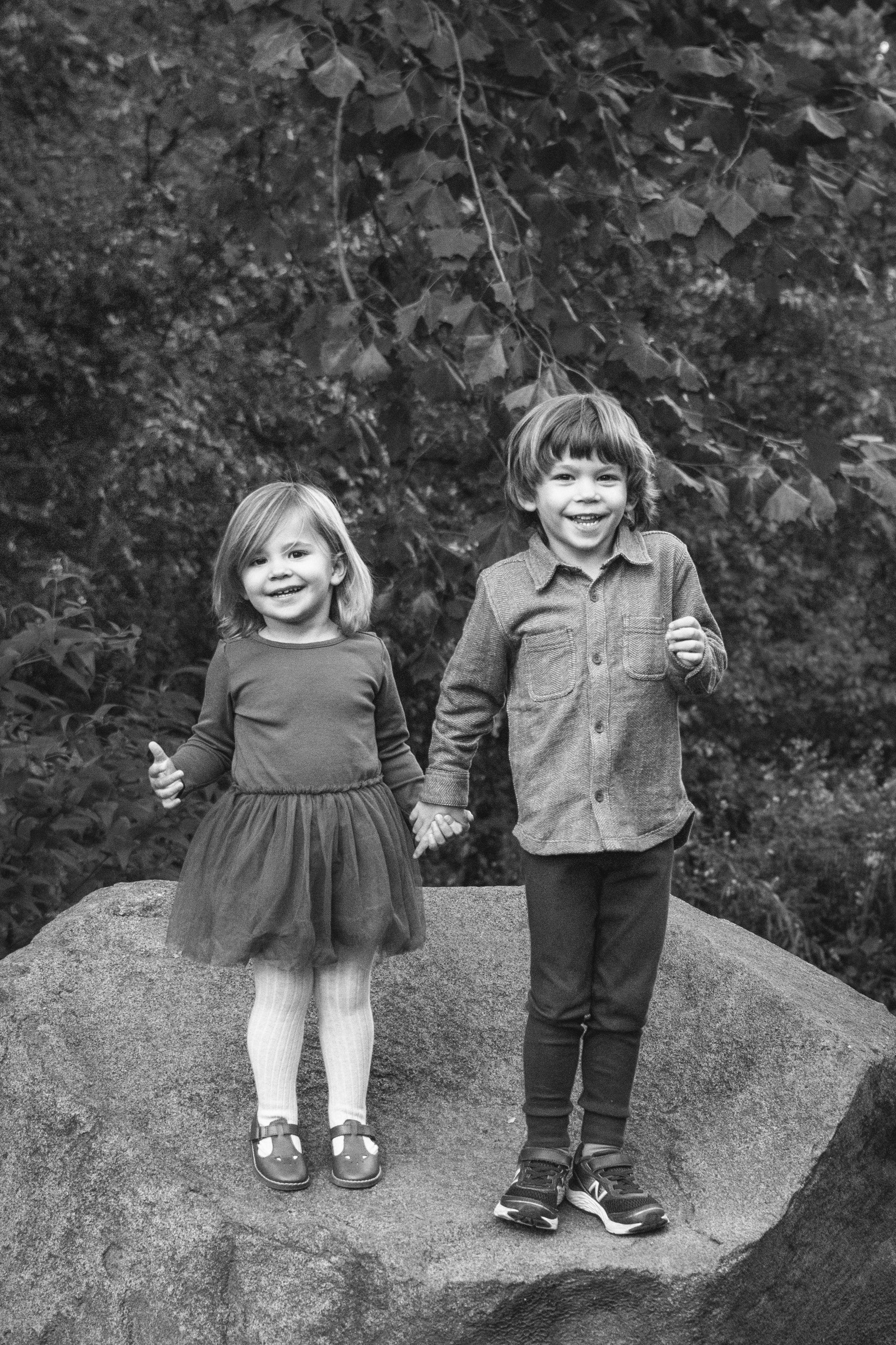  Black and white lifestyle portrait of a brother and sister holding hands in Central Park by Nicole Hawkins Photography. standing on a rock brother and sister #NicoleHawkinsPhotography #NicoleHawkinsFamilies #NJphotographers #familyphotos #CentralPar