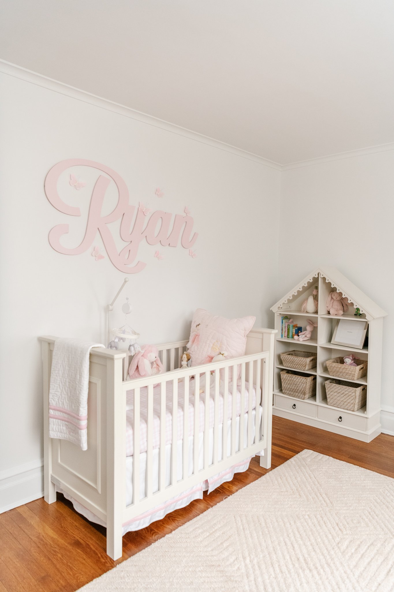  Nicole Hawkins Photography captures a little girls nursery with a pink wooden name sign on the wall above the crib. name sign in nursery pink and white girl nursery #NicoleHawkinsPhotography #NicoleHawkinsNewborns #Babygirl #Newbornfamilyportraits #