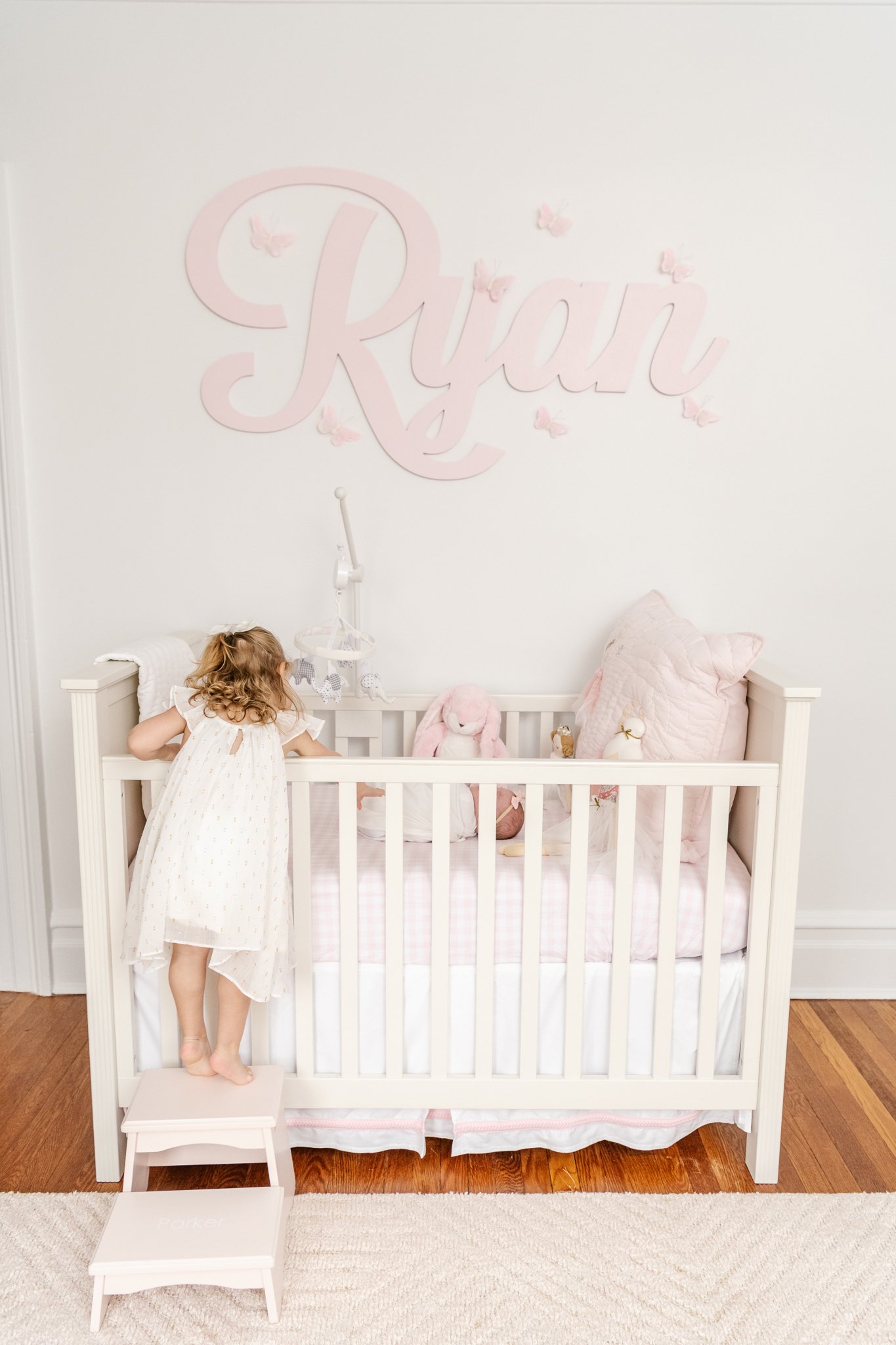  A toddler little girl is captured checking on her sister in her crib by Nicole Hawkins Photography. big sister toddler girl new baby #NicoleHawkinsPhotography #NicoleHawkinsNewborns #Babygirl #Newbornfamilyportraits #ChathamNewbornPhotographer #InHo
