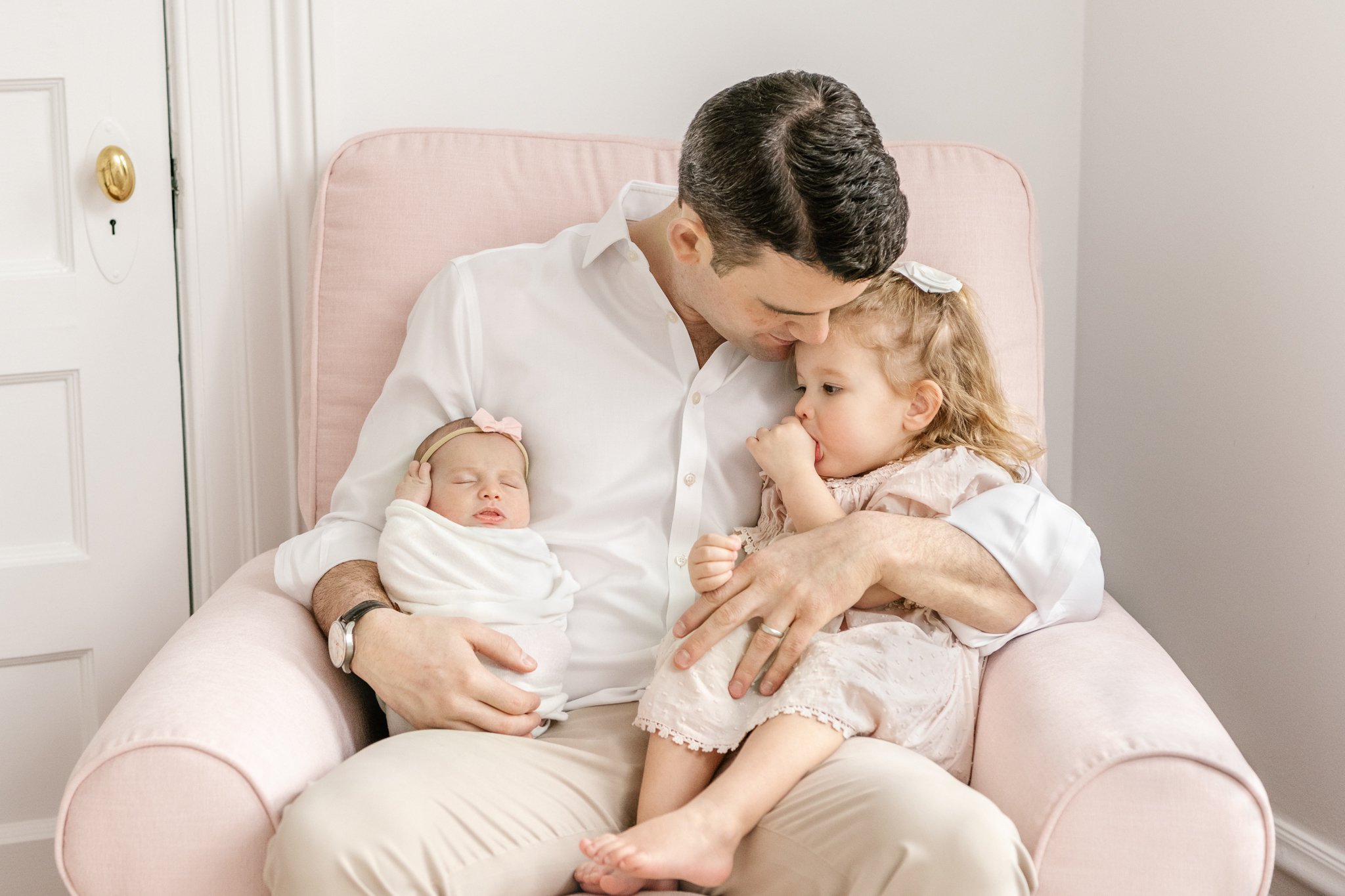  A father holds his two tiny girls in his arms and snuggles them tight captured by Nicole Hawkins's Photography. father daughter portrait family of four daddy daughter pictures #NicoleHawkinsPhotography #NicoleHawkinsNewborns #Babygirl #Newbornfamily