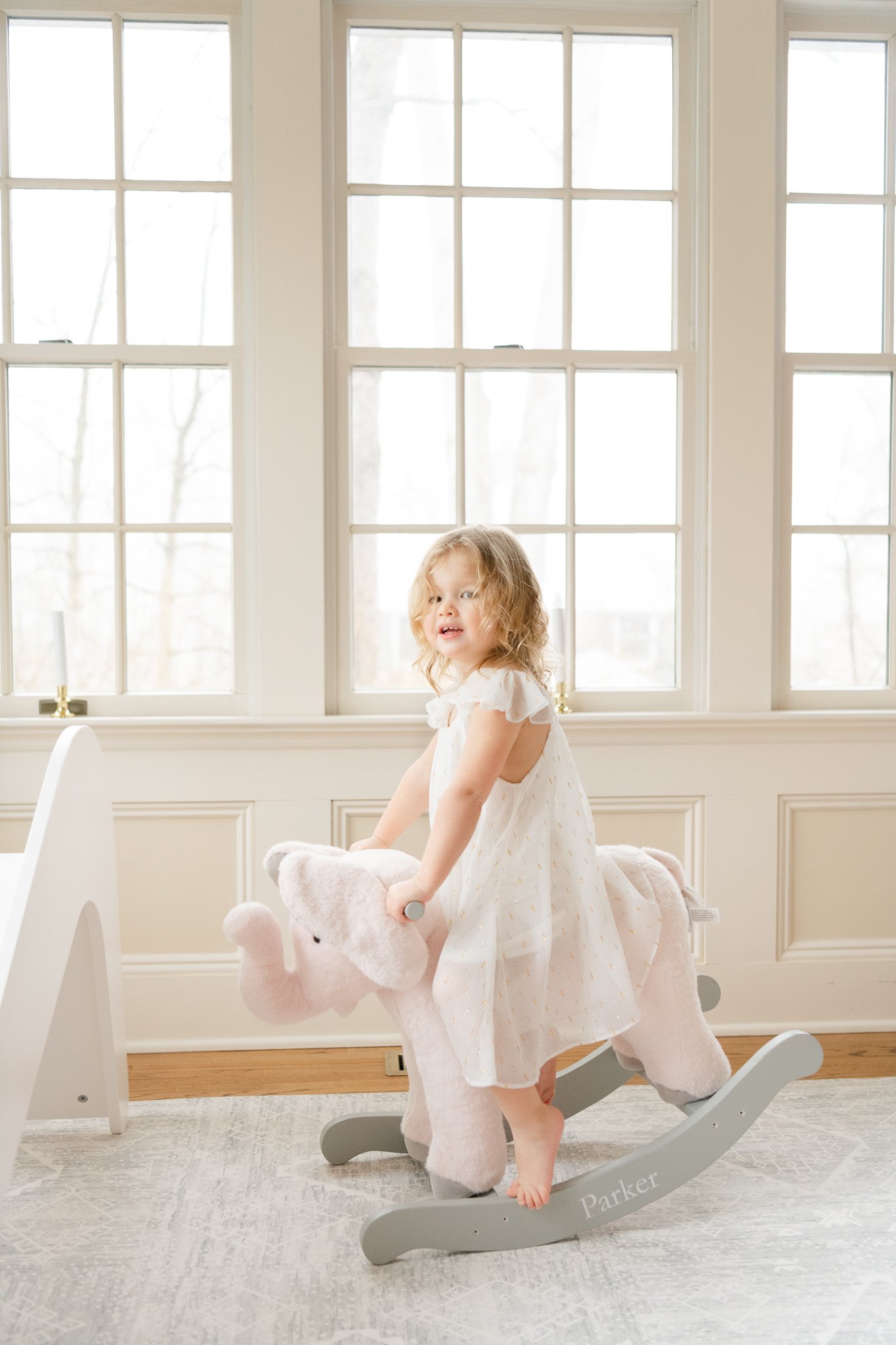  Nicole Hawkins's Photography captures a big sister playing on a wooden toy horse in the baby's nursery. rocking horse prop in home newborns toddler sister #NicoleHawkinsPhotography #NicoleHawkinsNewborns #Babygirl #Newbornfamilyportraits #ChathamNew