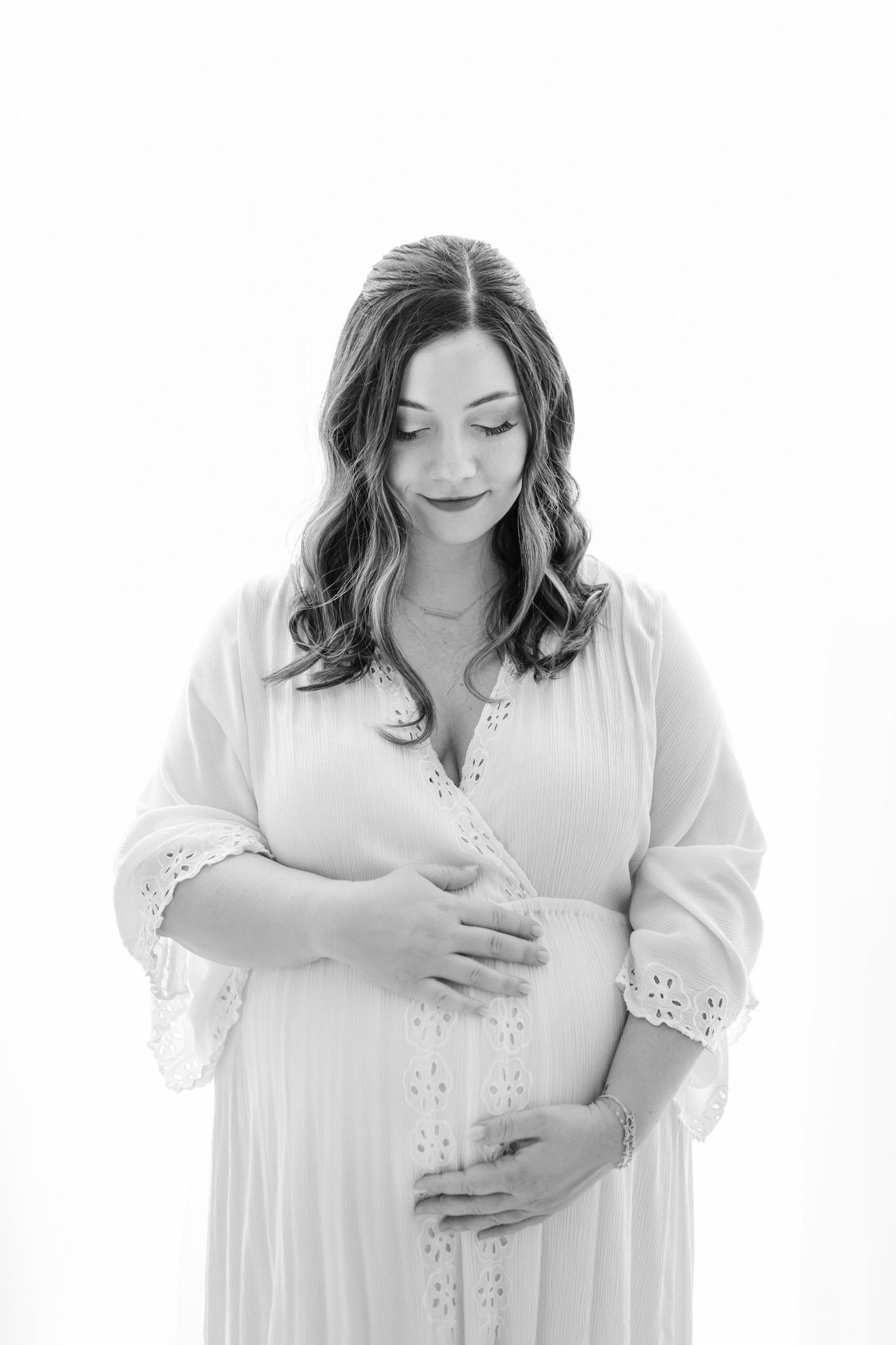  A black and white portrait of a pregnant woman holding her belly by Nicole Hawkins Photography in the New Jersey area. black and white maternity #NicoleHawkinsPhotography #NicoleHawkinsMaternity #Babyontheway #studiomaternityNJ #whitestudiomaternity