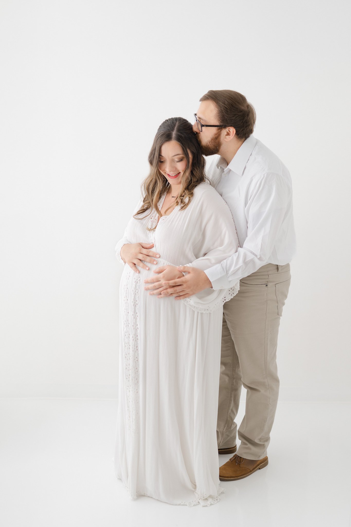  A husband and wife cuddle together during a studio session with Nicole Hawkins Photography. studio photographers modern maternity portraits #NicoleHawkinsPhotography #NicoleHawkinsMaternity #Babyontheway #studiomaternityNJ #whitestudiomaternityportr