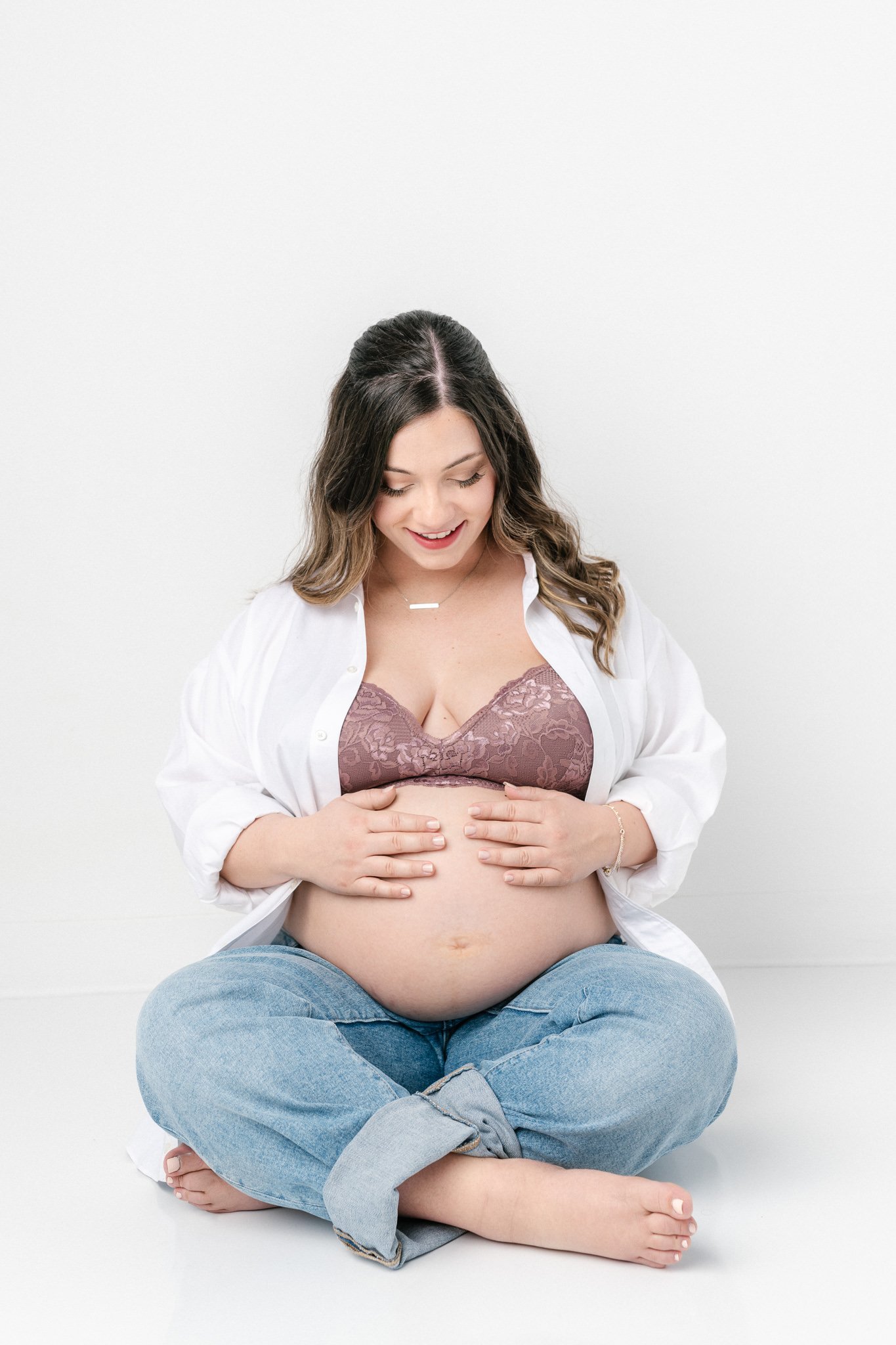  Maternity portrait of mother in jeans, bra, and white button-down shirt by Nicole Hawkins Photography. NJ studio portraits #NicoleHawkinsPhotography #NicoleHawkinsMaternity #Babyontheway #studiomaternityNJ #whitestudiomaternityportraits #NYmaternity