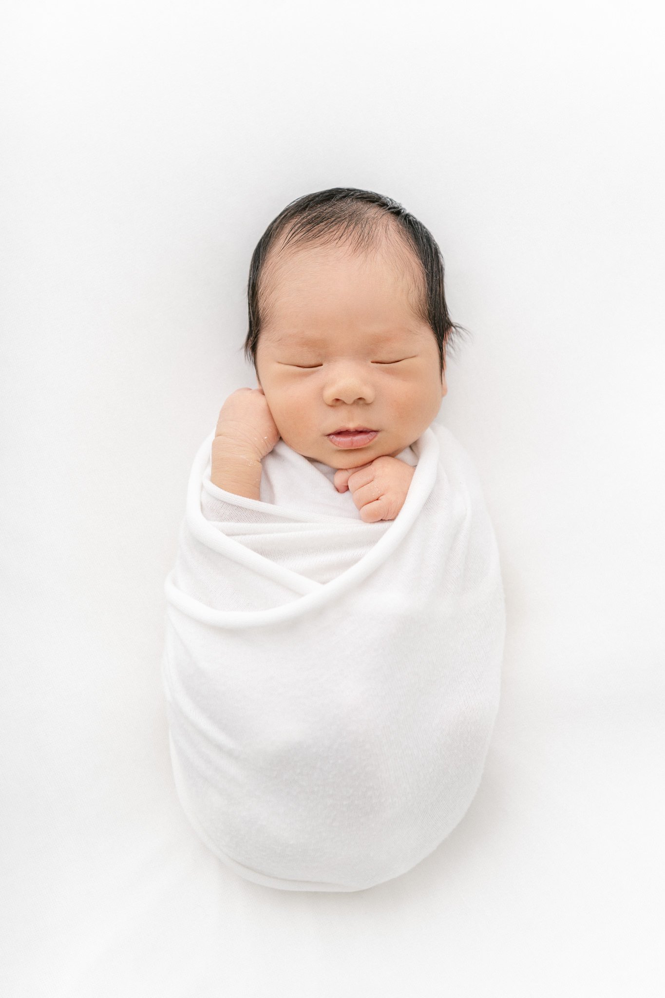  A swaddled newborn baby boy sleeps during an all white studio newborn session by Nicole Hawkins Photography. swaddled newborn portrait studio newborns East Coast #NicoleHawkinsPhotography #NicoleHawkinsNewborns #Babyboy #studionewbornsNJ #studionewb