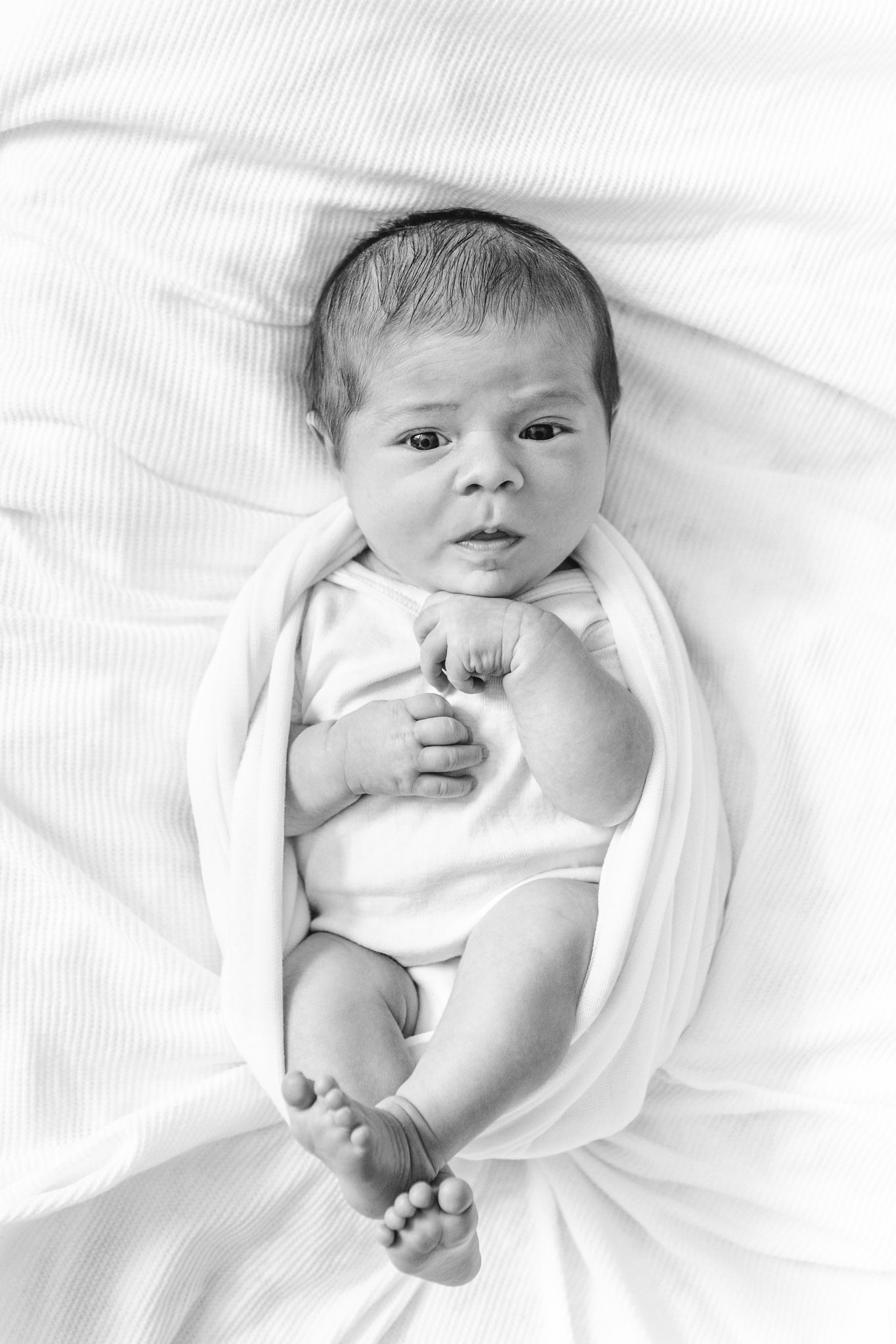  Nicole Hawkins Photography captures a black and white portrait of a swaddled newborn on a bed. swaddle black and white portraits of newborns #NicoleHawkinsPhotography #NicoleHawkinsNewborns #Babygirl #inhomenewbornsNJ #homenewbonportraits #inhomenew