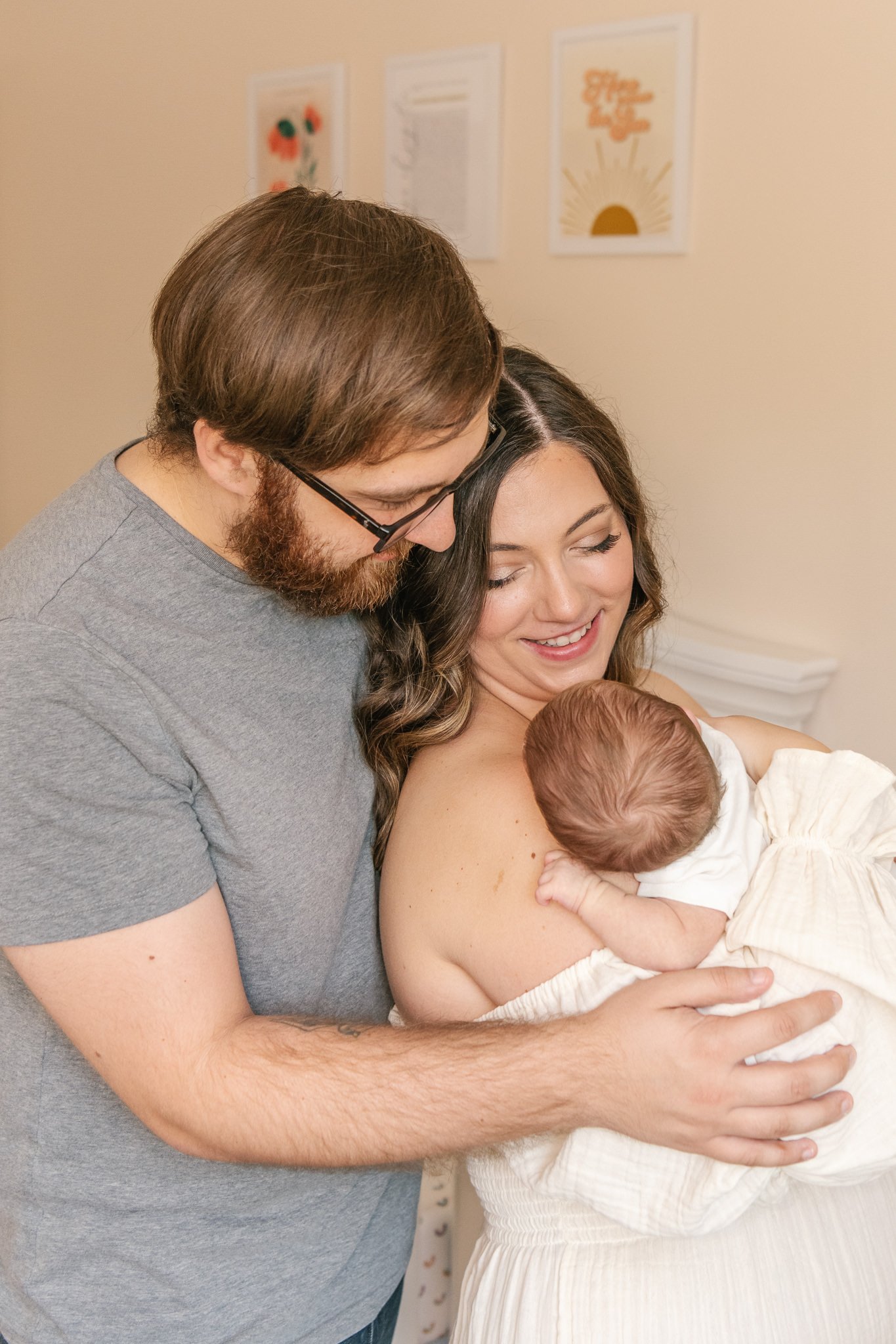  Father holds his wife and newborn in his arms snuggling them tight by Nicole Hawkins Photography. family of three newborn baby girl #NicoleHawkinsPhotography #NicoleHawkinsNewborns #Babygirl #inhomenewbornsNJ #homenewbonportraits #inhomenewborns #NJ