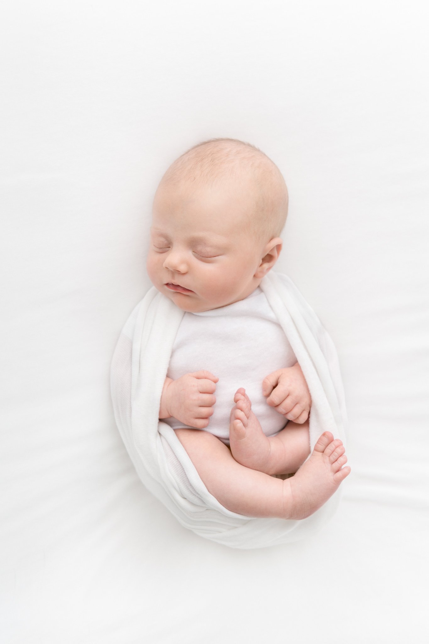  New Jersey studio newborn session with a swaddled sleeping baby girl by Nicole Hawkins Photography. bald baby portrait sleeping swaddle for newborns to show off legs #NicoleHawkinsPhotography #NicoleHawkinsNewborns #StudioNewborn #StudioFamily #East