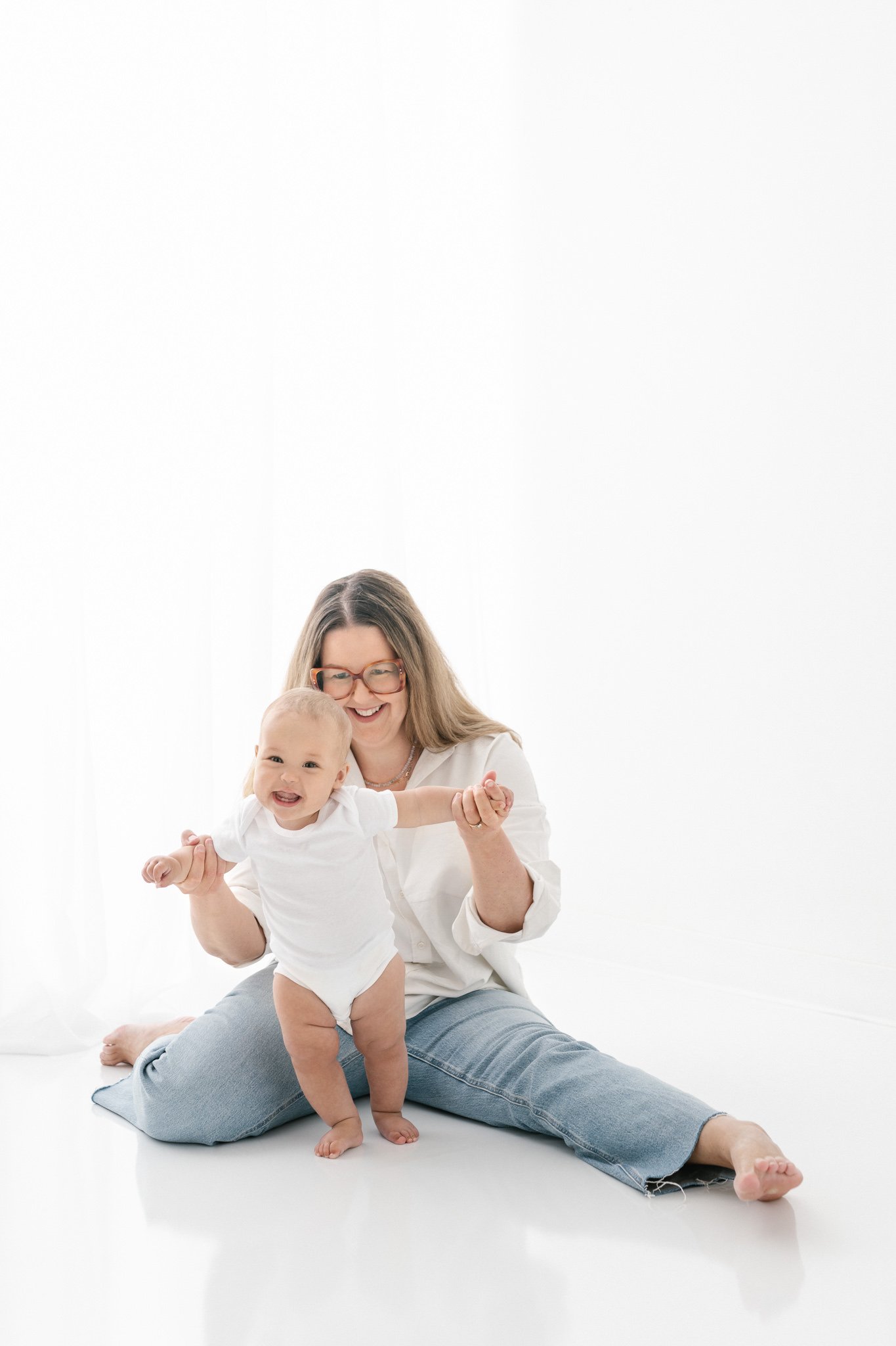  A baby holds onto her momma's hands and tries to walk captured by Nicole Hawkins Photography. chunky baby thighs smiley baby walking baby feet #NicoleHawkinsPhotography #NicoleHawkinsNewborns #studionewborns #studioportraits #babystudioportraits #Ne