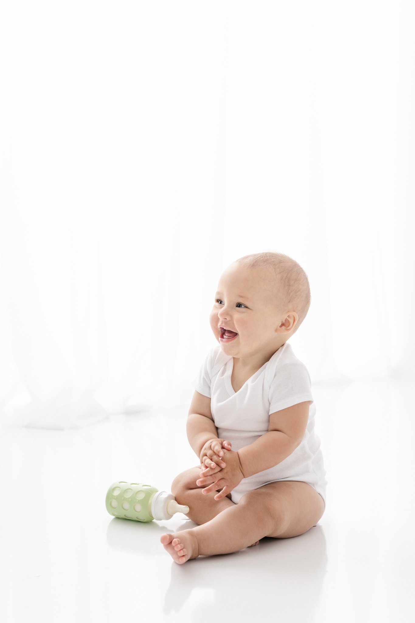  A baby laughs at her mother with a bottle sitting beside her by NJ studio photographer Nicole Hawkins Photography. studio photography New Jersey #NicoleHawkinsPhotography #NicoleHawkinsNewborns #studionewborns #studioportraits #babystudioportraits #