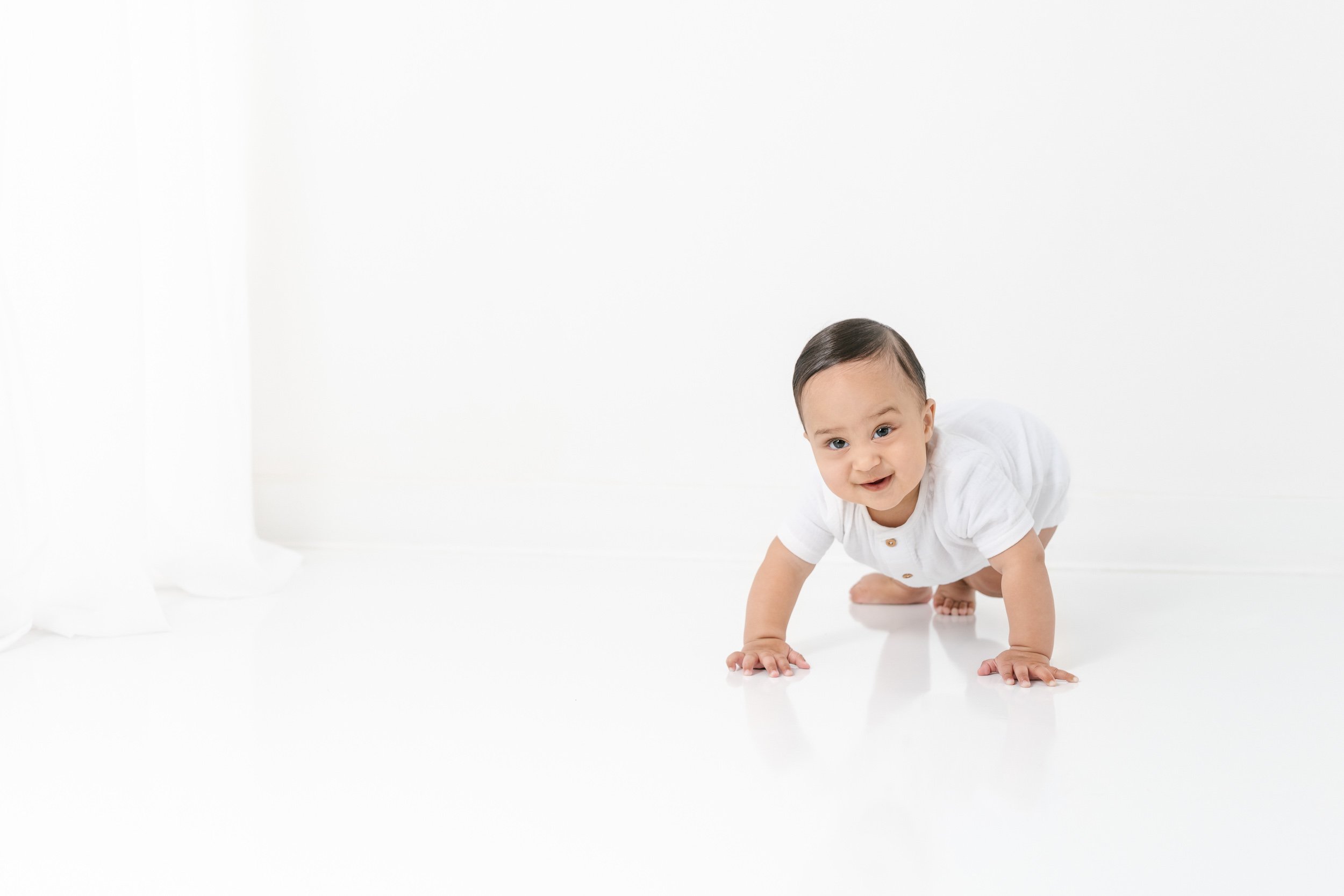  Nicole Hawkins's photography captures a baby boy crawling around a studio during a child portrait session. crawling baby boy baby in white outfit milestone portraits #NicoleHawkinsPhotography #NicolewHawkinsNewborns #NewJerseyNewborns #NewJerseyStud
