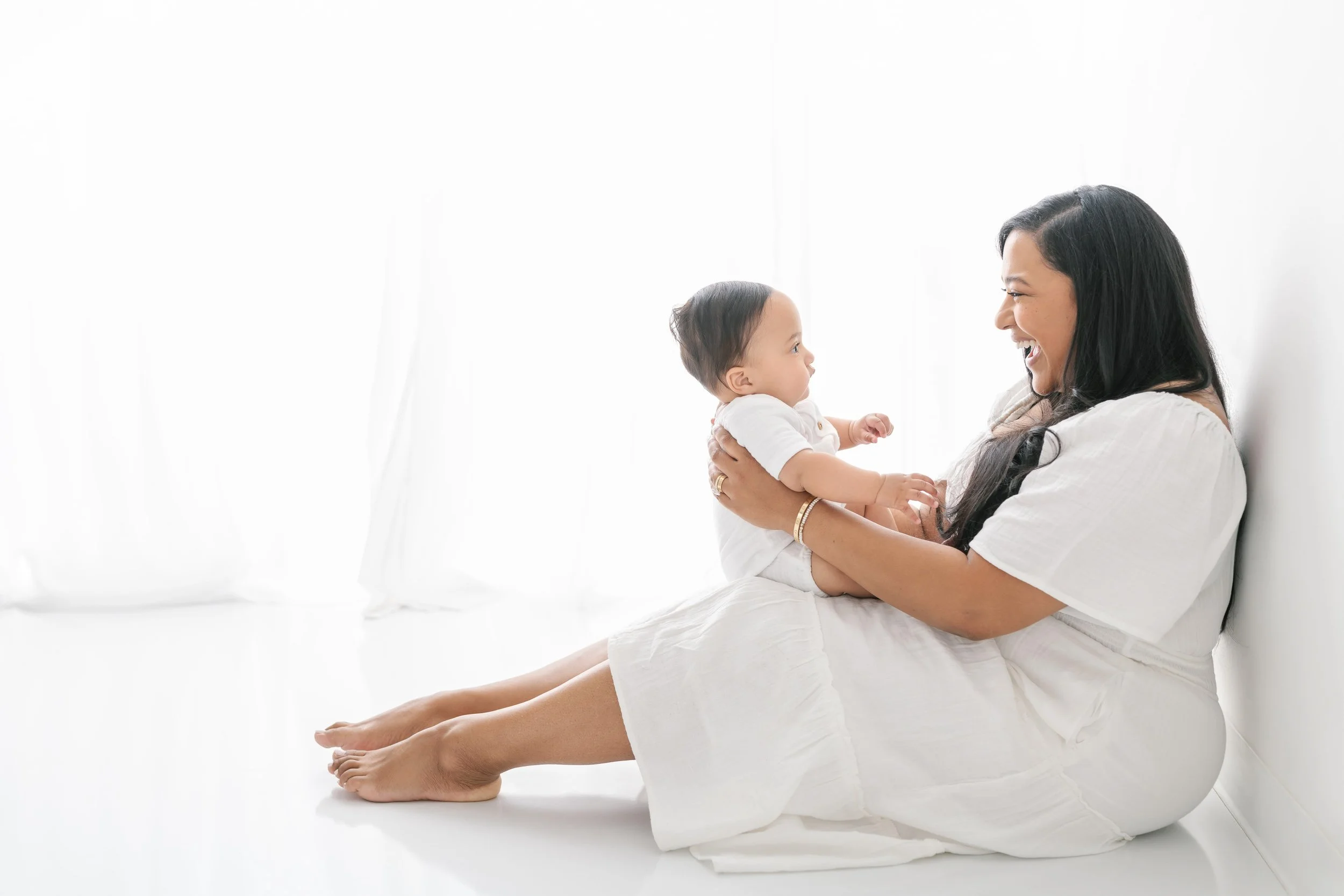  A mother plays games with her baby boy during a family studio session in NJ by Nicole Hawkins Photography. baby boy sitting on mother lap playing games #NicoleHawkinsPhotography #NicolewHawkinsNewborns #NewJerseyNewborns #NewJerseyStudioNewborns #St