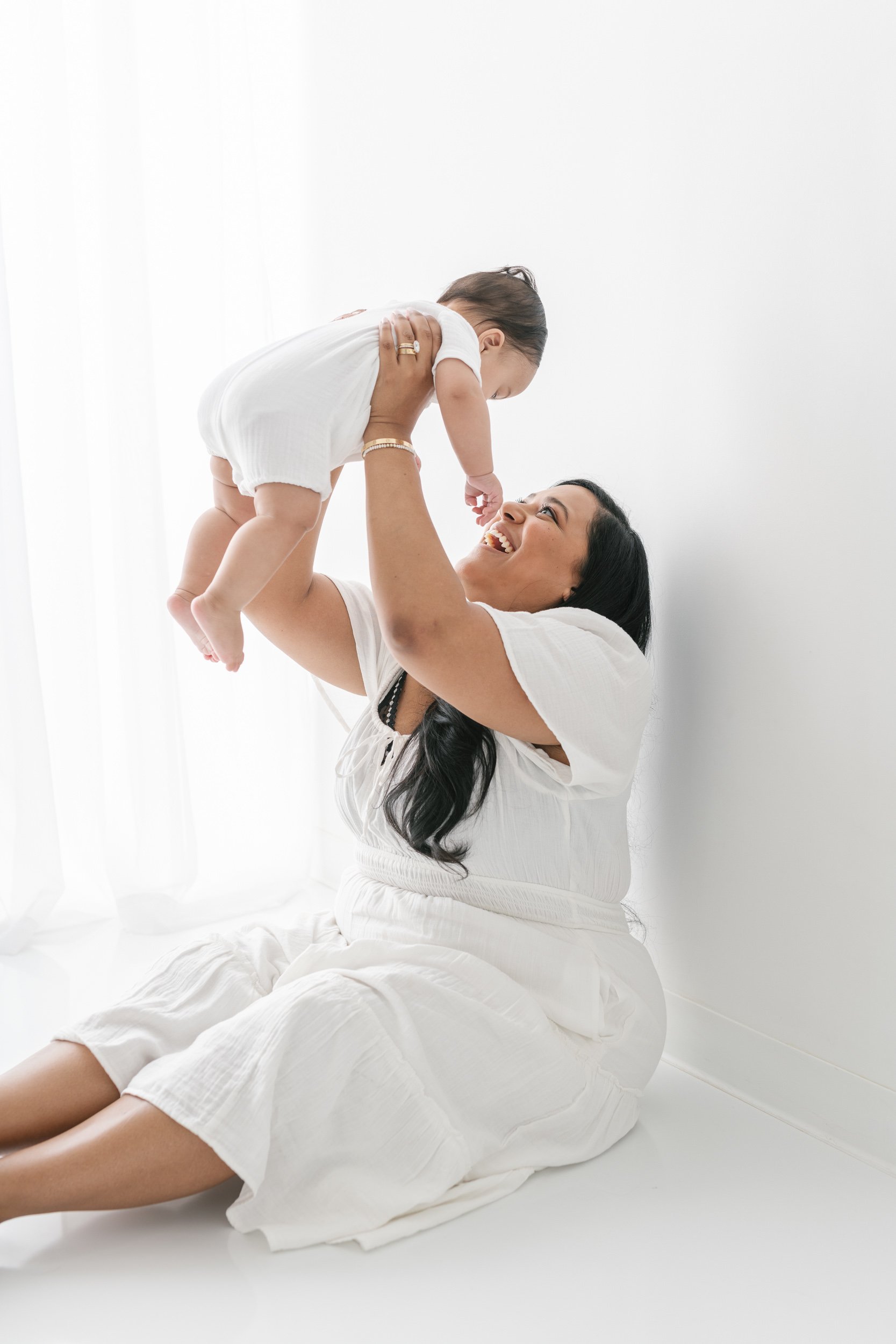  A mother lifts her baby in the air and smiles at him in New Jersey by Nicole Hawkins Photography. mother holding a baby boy in air toddler baby portraits motherhood #NicoleHawkinsPhotography #NicolewHawkinsNewborns #NewJerseyNewborns #NewJerseyStudi