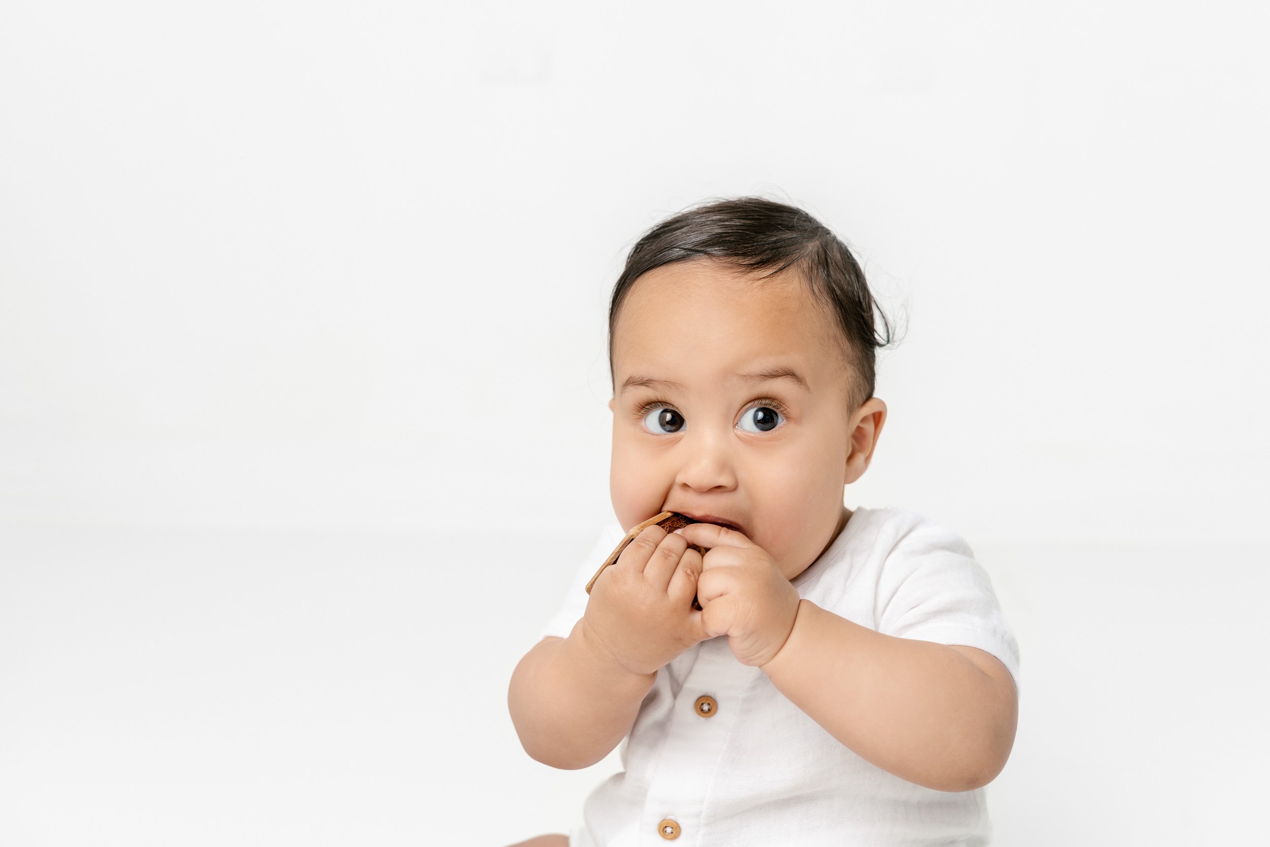  Nicole Hawkins Photography took A milestone portrait of a baby boy putting things in his mouth and exploring. black hair brown eyes baby chunky one-year-old toddler boy #NicoleHawkinsPhotography #NicolewHawkinsChildren #NewJerseyStudioBabies #Studio