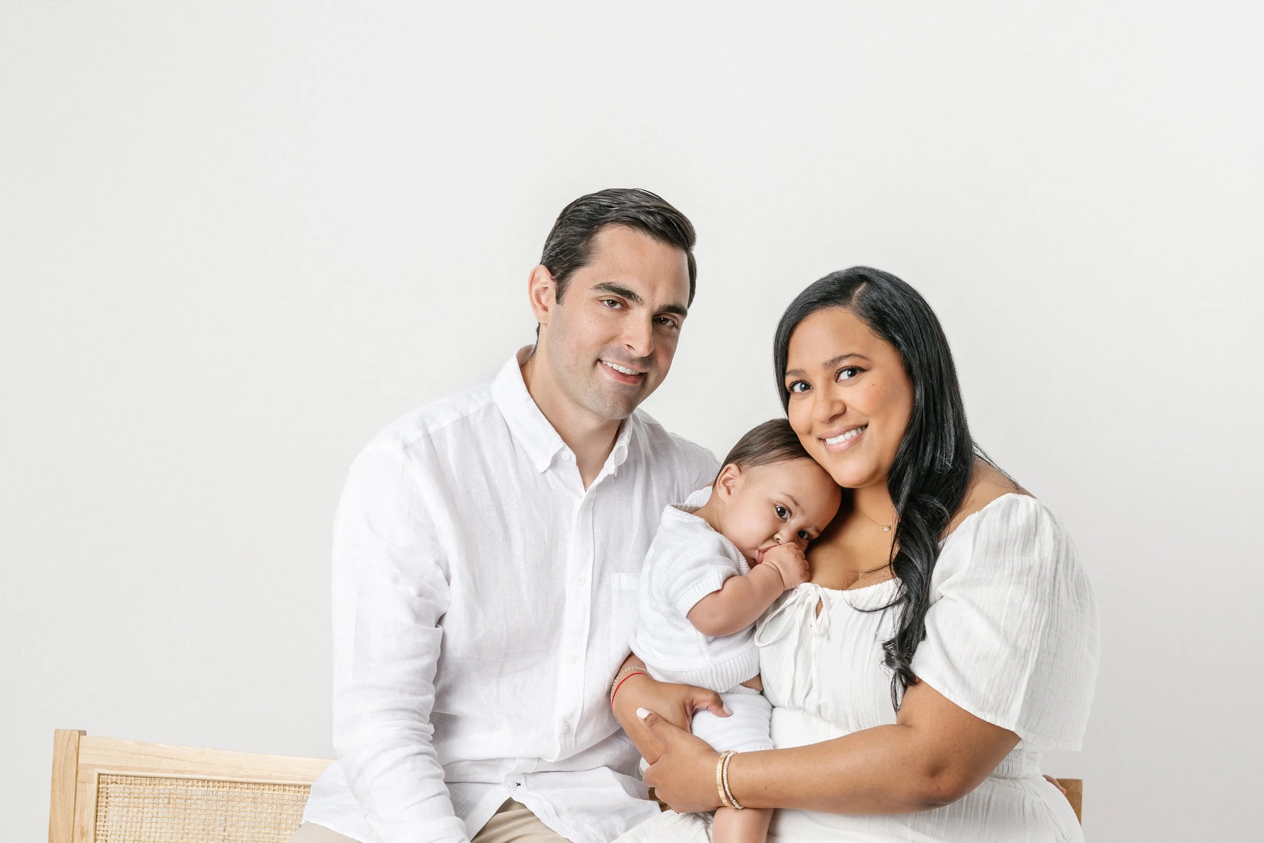  Nicole Hawkins Photography captures a baby boy snuggling into his mother's shoulder during a family portrait. family portrait black hair family snuggly baby #NicoleHawkinsPhotography #NicolewHawkinsChildren #NewJerseyStudioBabies #StudioNewborn #Stu