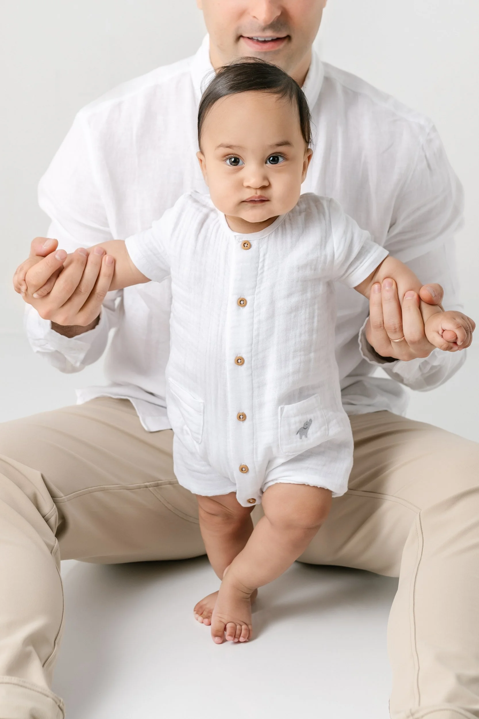  With daddy holding his hands, a baby boy tries to walk, captured by Nicole Hawkins Photography, an NJ studio photographer. studio portraits east coast walking baby #NicoleHawkinsPhotography #NicolewHawkinsNewborns #NewJerseyNewborns #NewJerseyStudio