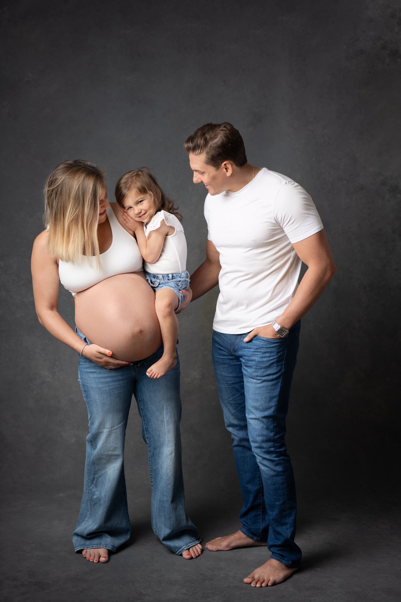  A family with a little girl and an expecting mother take portraits in a studio by Nicole Hawkins Photography. expecting mother family photos jeans and t-shirt family portraits #NicoleHawkinsPhotography #NicoleHawkinsMaternity #MaternityStudioPortrai