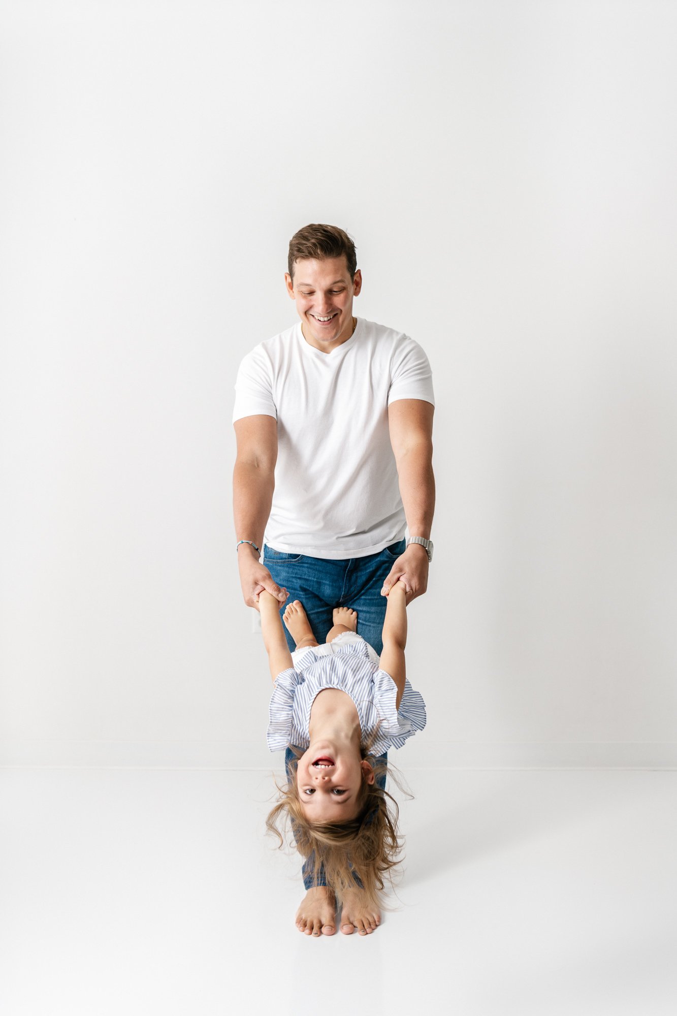  Nicole Hawkins Photography, an NJ family photographer, captures a father playing with his little girl in an all-white studio. daddy daughter pic dad style for studio family photography #NicoleHawkinsPhotography #NicoleHawkinsMaternity #MaternityStud