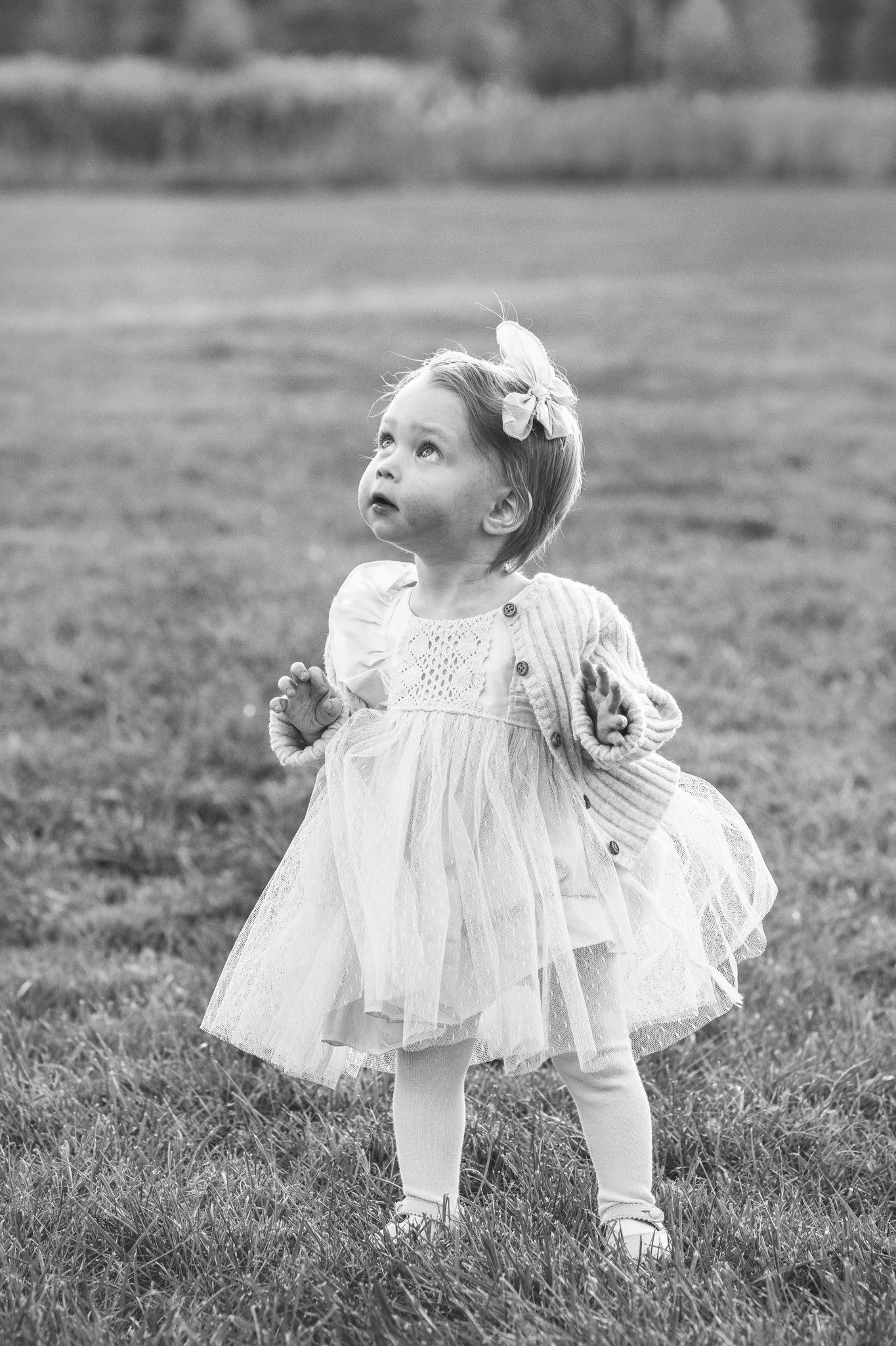  NJ family photographer Nicole Hawkins Photography captures a portrait of a little girl walking around looking up. black and white portrait of a little girl with tights and gold shoes #NicoleHawkinsPhotography #NicoleHawkinsFamilies #FallFamilyPhotos