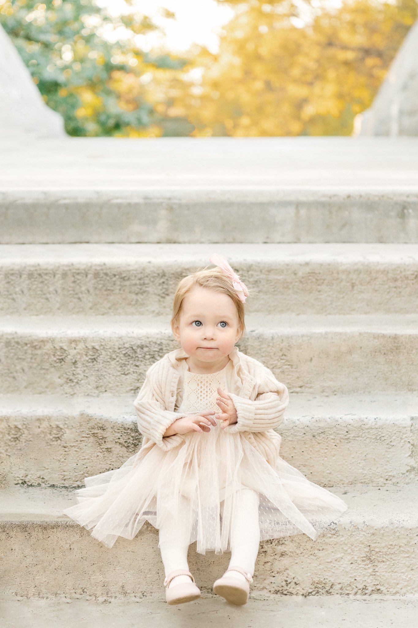  A darling toddler little girl with a tulle dress and pink bow sits on the stairs by Nicole Hawkins Photography in NJ. reasons to take family pics in the fall #NicoleHawkinsPhotography #NicoleHawkinsFamilies #FallFamilyPhotos #FallPortraits #NJFamily