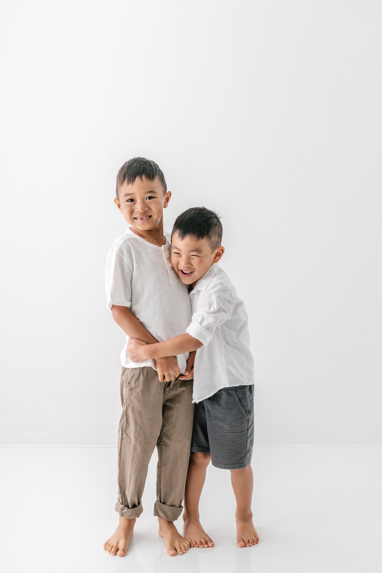    Two happy brothers sharing a hug at a newborn family photo session captured by Nicole Hawkins Photography in New Jersey. #studionewborns #studioportraits #babystudioportraits #NewJerseyPhotographers #NJfamilyphotographer   