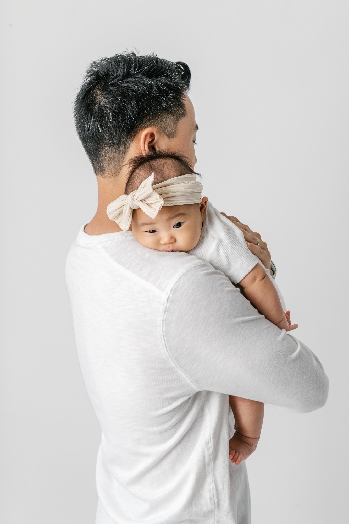    Newborn baby girl placed over father’s shoulder while father is turned away. Sleepy baby captured in tender moment with dad by Nicole Hawkins Photography in studio in New Jersey&nbsp; #studionewborns #studioportraits #babystudioportraits #NewJerse