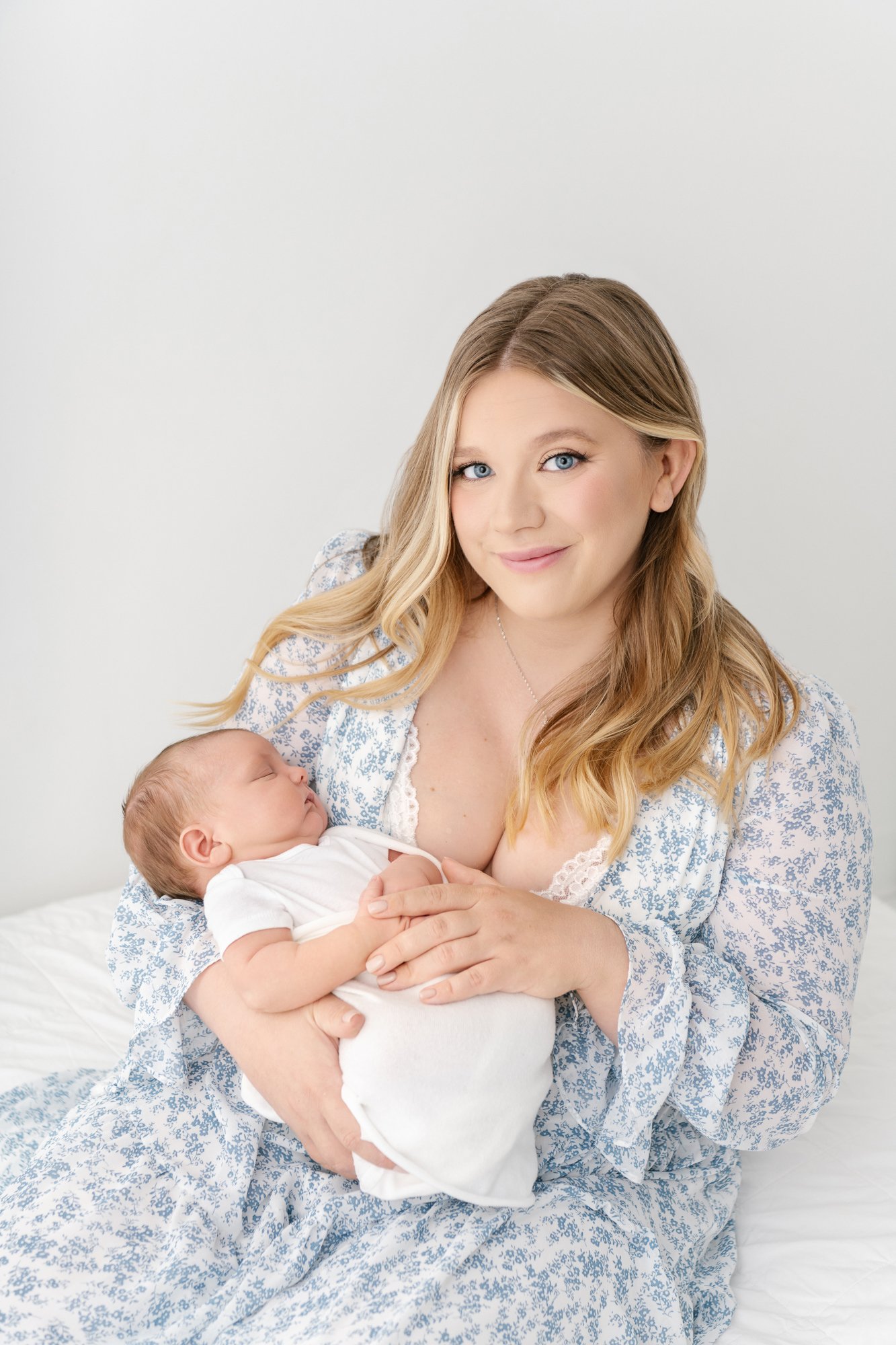    Beautiful young mom gazes up at the camera with a sweet smile while holding swaddled newborn baby. Newborn studio outfit inspiration. Studio photo session by Nicole Hawkins Photography&nbsp; #newbornportraits #newbornstudioshoots #NewJerseyPhotogr