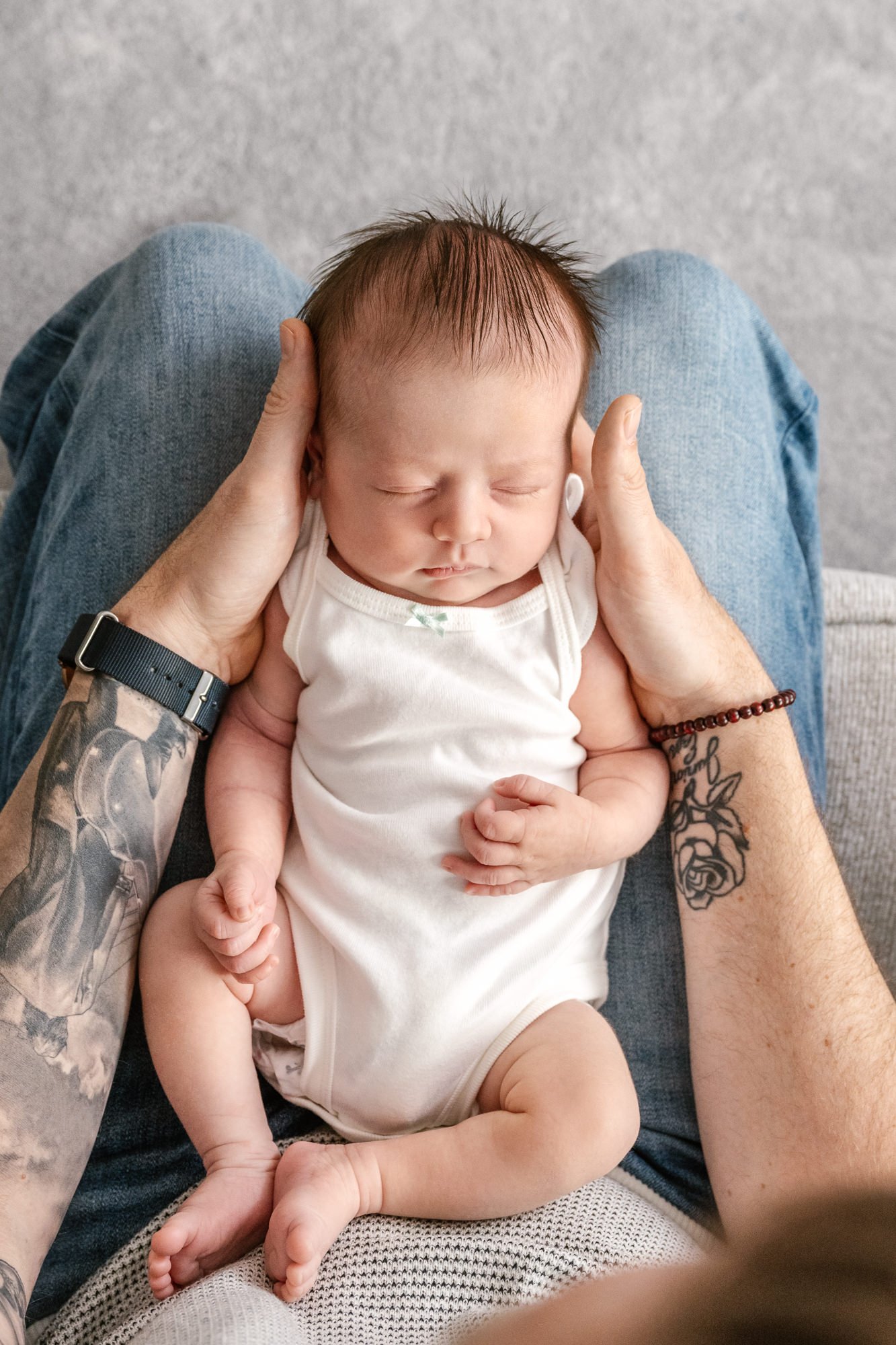  An aerial shot taken by Nicole Hawkins photography of a dad who lays newborn baby on his lap and holds her on his forearms. North Central New Jersey in-home newborn photo session. #centralNewJerseyphotographer #inhomeportraits #newbornphotoshoot #Ne