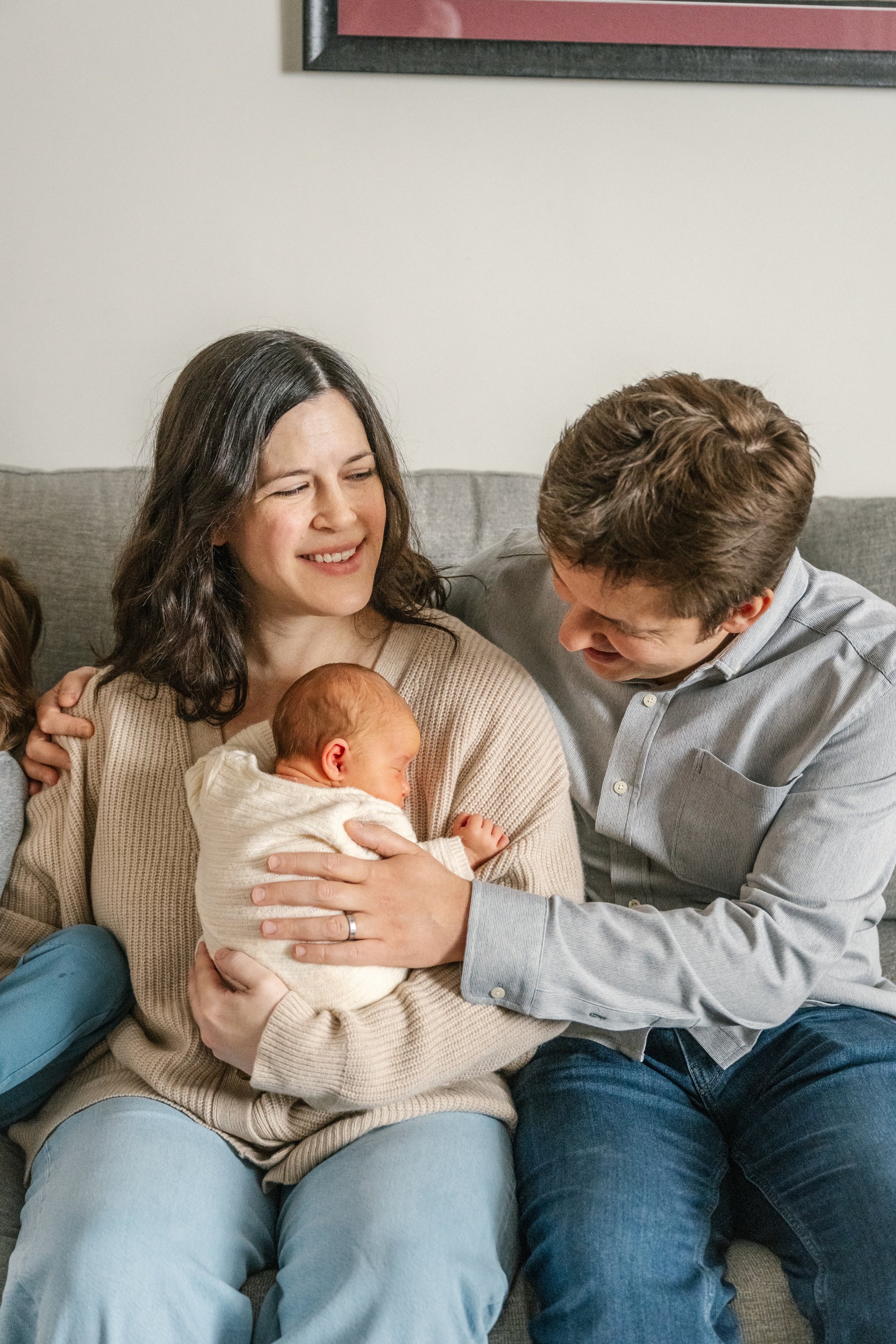   At home family photo of mom and dad sitting on a couch,&nbsp; playing with their newborn baby. Casual in-home family photoshoot inspiration #EssexCountyFamilyPhotographer #PassaicCountyFamilyPhotographer #NorthernNewJerseyFamilyPhotographer #Manhat