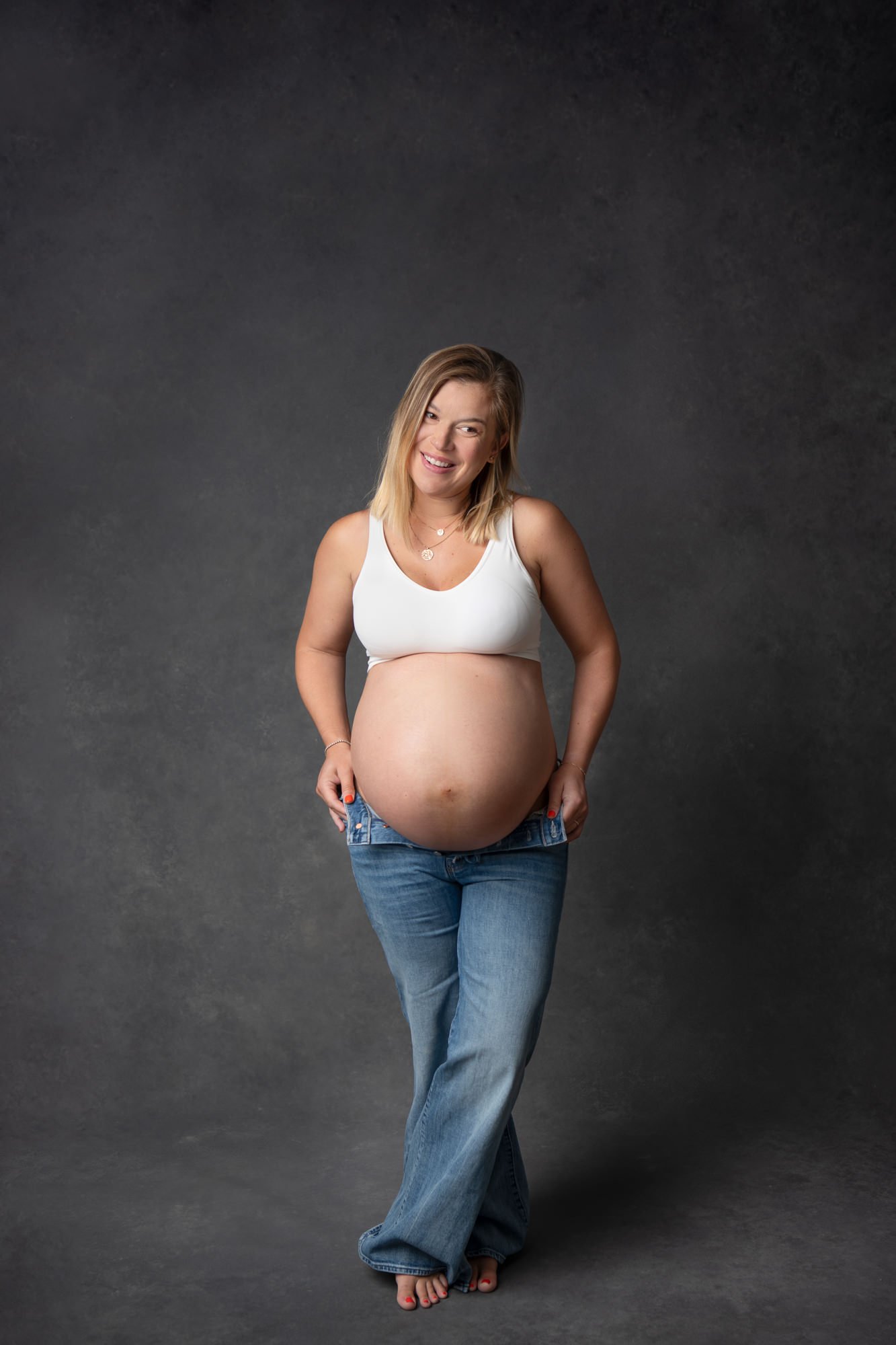   Mom-to-be posing during maternity photoshoot, wearing jeans and a white top. Pregnancy photo pose ideas Maternity portrait ideas #EssexCountyFamilyPhotographer #BergenCountyFamilyPhotographer #NorthernNewJerseyFamilyPhotographer #NorthernNewJerseyP