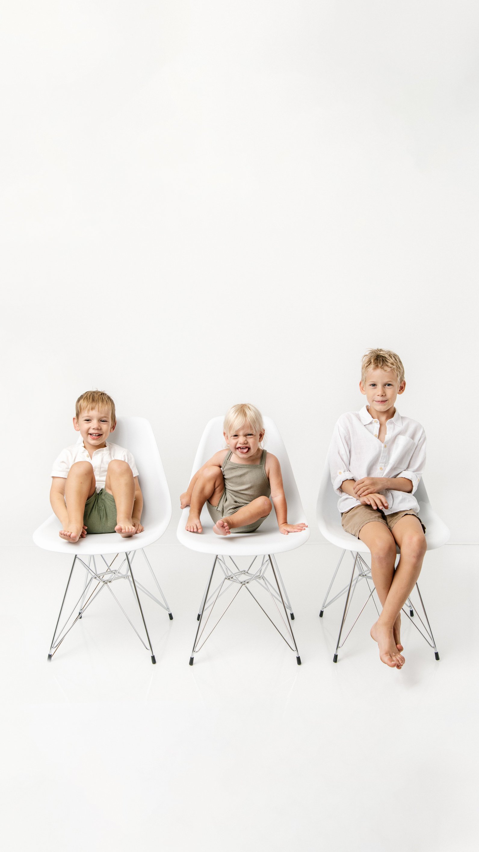   Classic sibling portrait of three kids sitting in chairs smiling at the camera, taken by New Jersey family photographer Nicole Hawkins. Sibling photo pose ideas #UnionCountyFamilyPhotographer #PassaicCountyFamilyPhotographer #ManhattanFamilyPhotogr