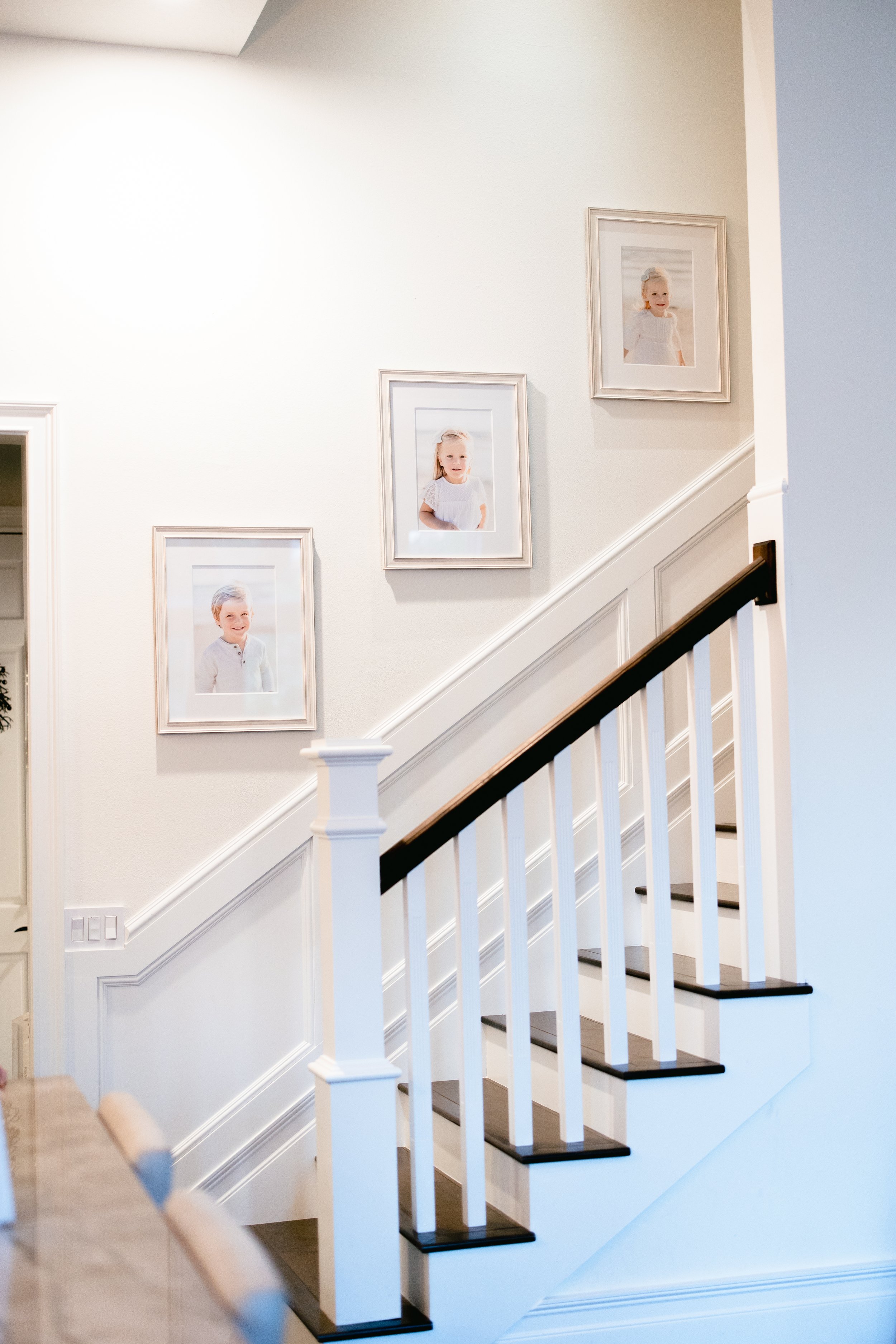   Children’s portraits hung above stairs with white frames and mats. Family portrait display inspiration family photo ideas #UnionCountyFamilyPhotographer #MorrisCountyFamilyPhotographer #NorthernNewJerseyFamilyPhotographer #NorthernNewJerseyPhotogra