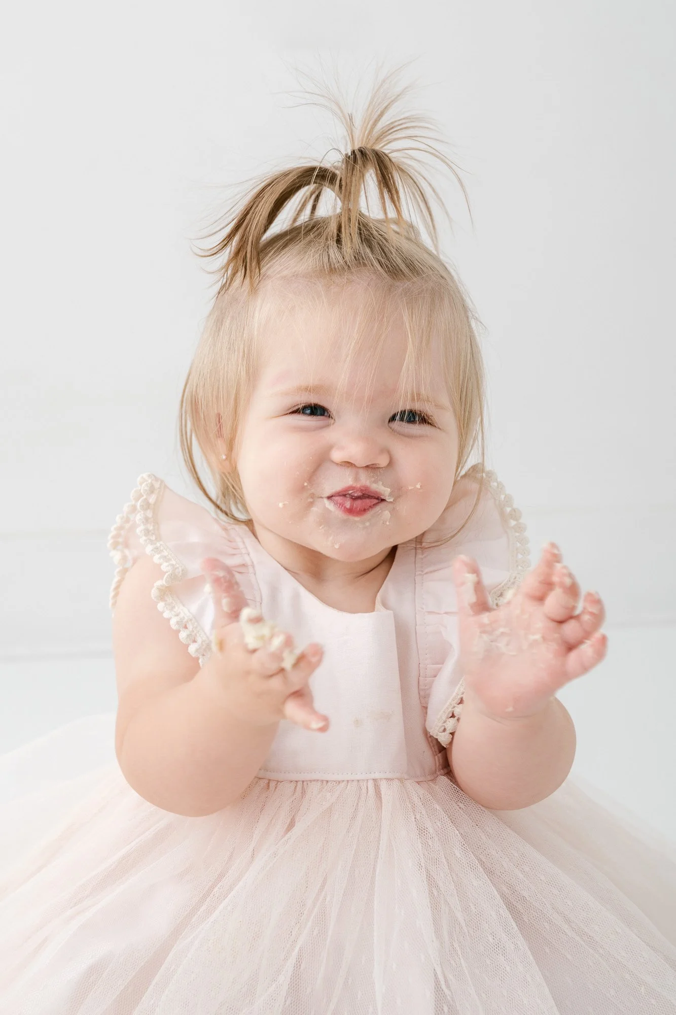  Happy baby with cake on her face wearing beautiful soft pink dress from NJ photographer’s studio wardrobe 