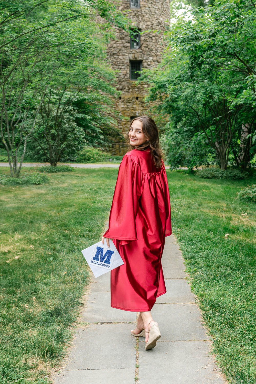 Graduating senior walking with a graduation cap decorated for her college at Cross Estate Gardens
