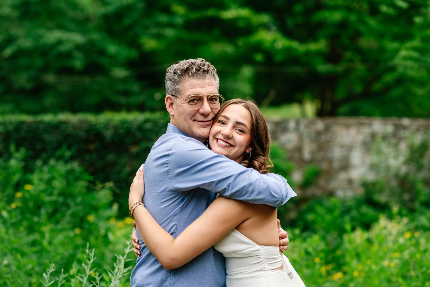 Hugging father and senior daughter portrait during her senior photography session in NJ garden