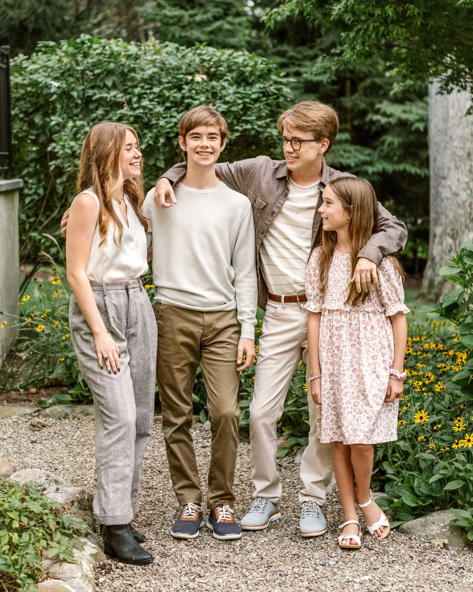 A group of four teenagers, two boys and two girls, standing together in Summit NJ backyard, smiling and enjoying each other's company.