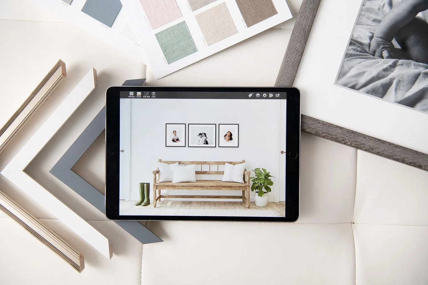 Ipad showing family photo design options, surrounded by photo frame corners, family album cover watches and framed baby portrait