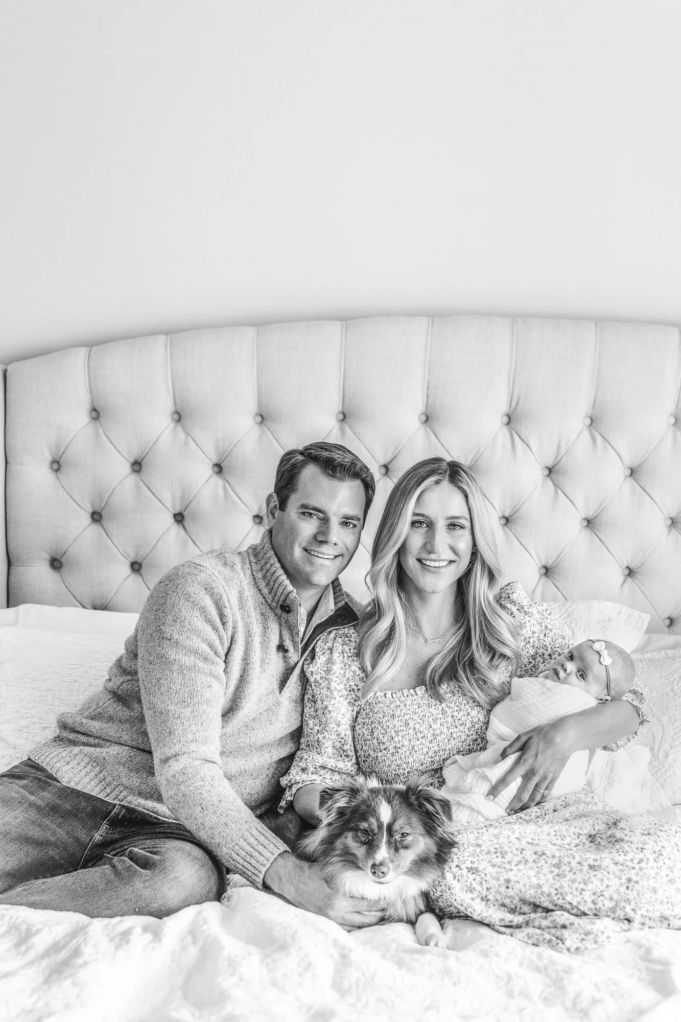 Family at home with newborn baby and dog looking at camera