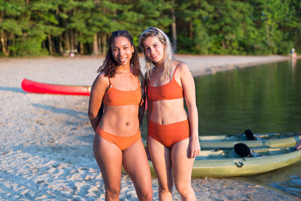 Two girlfriends smiling at camera, in terra-cotta orange bikinis 