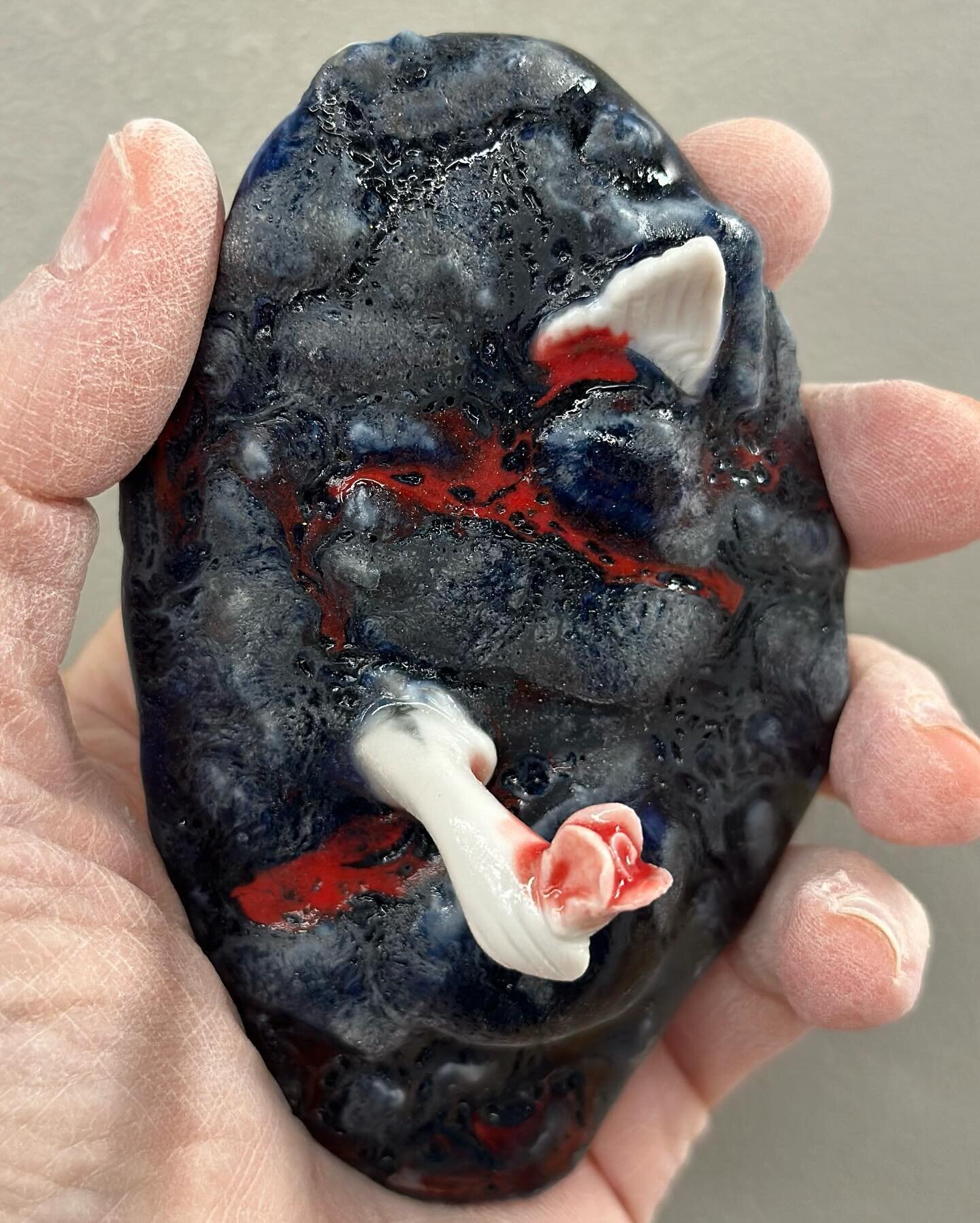 Porcelain figurine limbs in lump of clay; red, cobalt, and black glazes - although I forgot what I put on there, tbh #foundobjects #foundobject #ceramics #2023