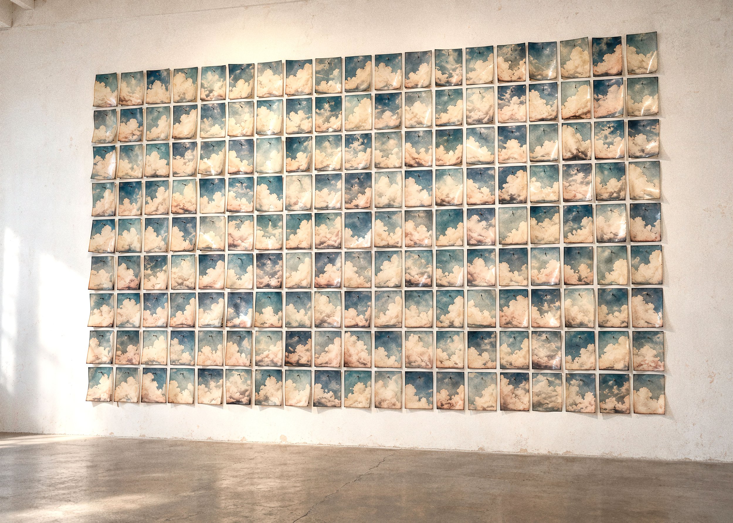 Installation view of Joost Vandebrug’s Moment in Time: a grid of cloud photographs on a gallery wall.
