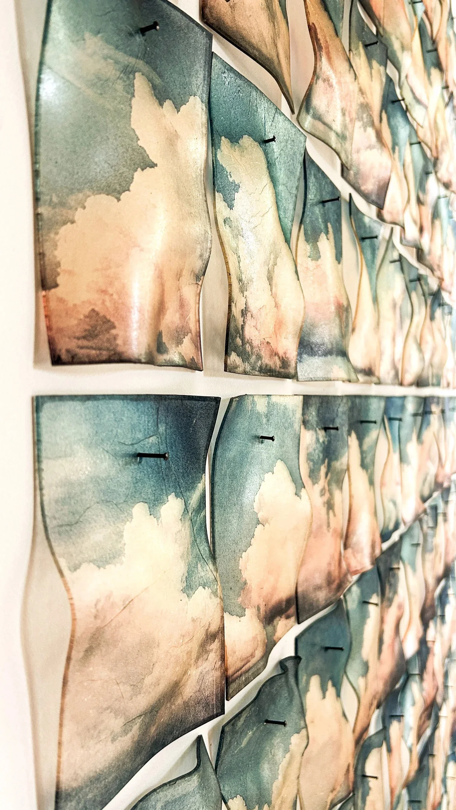 Close view of rows of curved cloud panels mounted on a wall, each showing a different cloud formation.