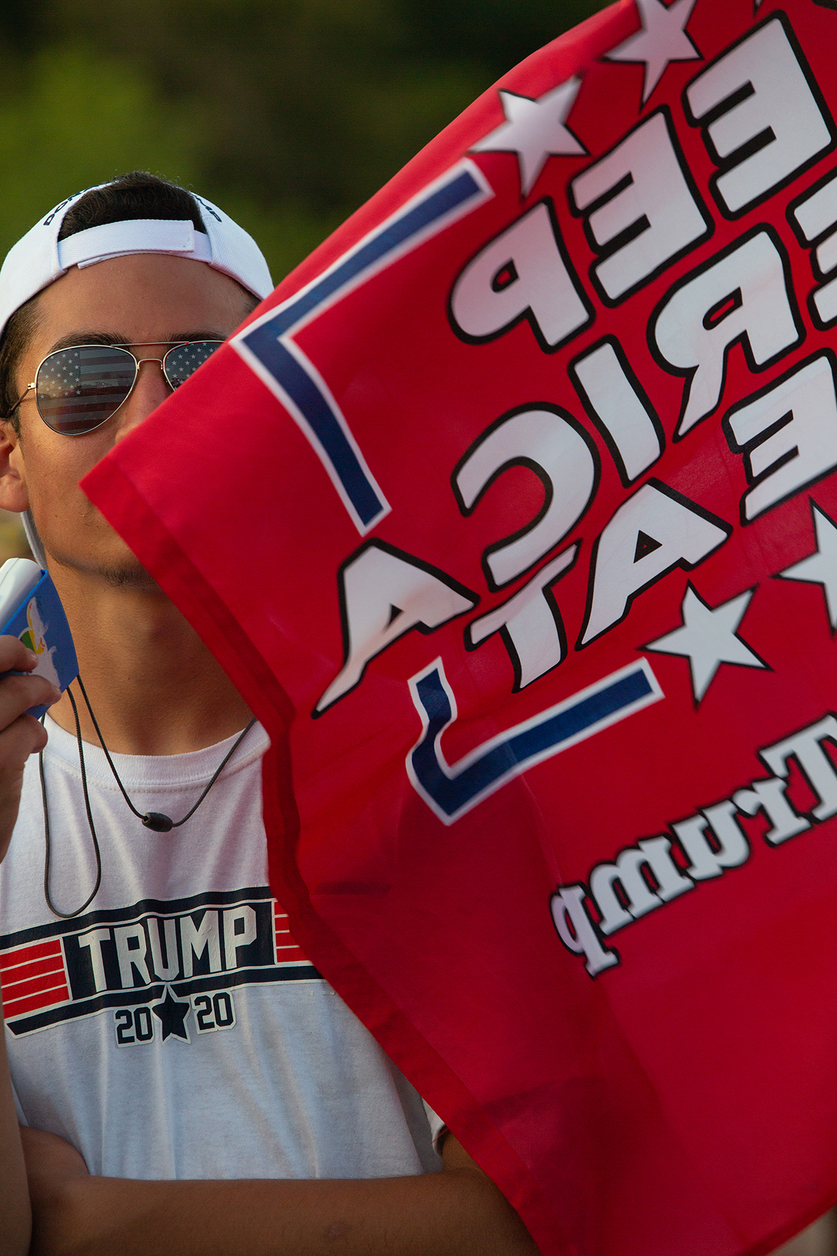  A man sells merchandise as Trump supporters congregate outside Williams Arena on East Carolina University's campus on July 17, 2019 in Greenville, NC. The "Send her back!" chant—referring to Rep. Ilhan Omar—debuted at this rally. (For The Atlantic) 