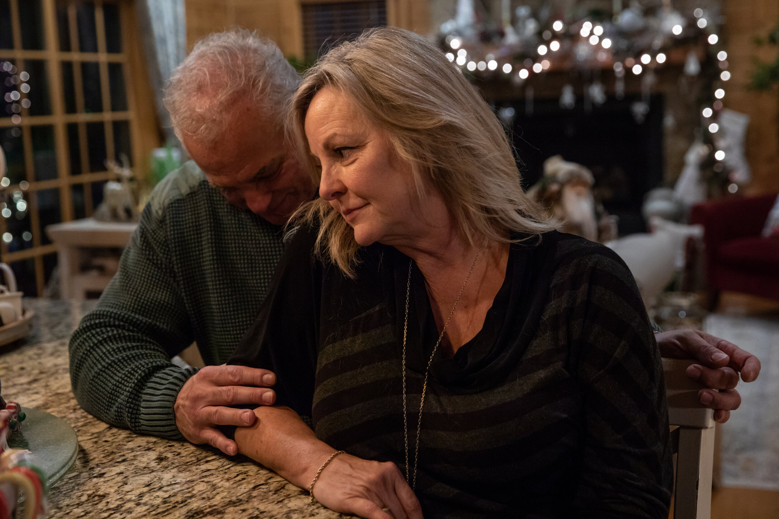  Mark and Cindy Bezzek sit at a counter in their home in Sanford, North Carolina, on Dec. 19, 2020. Bezzek and her husband, Mark, lost their mothers to COVID-19; their daughter died of an overdose after not being able to receive care because rehabili