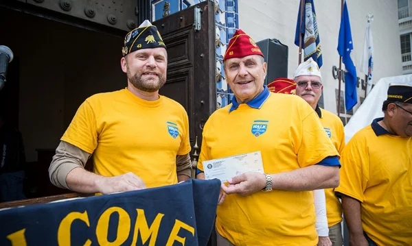 Hollywood Post 43 2nd Vice Commander Michael Hjelmstad presents a donation check to American Legion National Commander Charles E. Schmidt for his fundraising project during Post 43's Walk for Veterans Dec. 11, 2016. (Photo by Jon Endow/The American Legion)