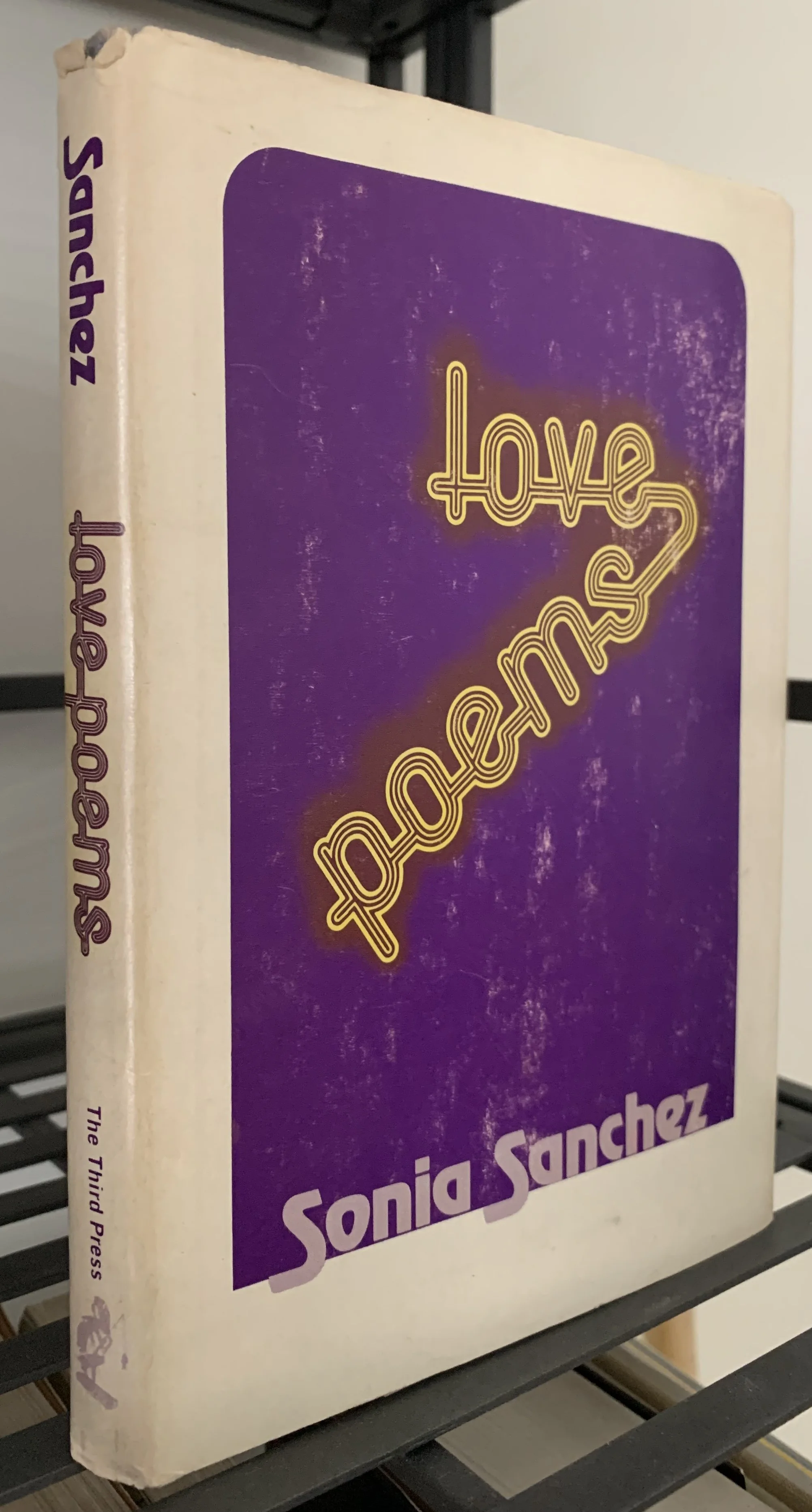 a book measuring 8x5 inches sitting upright showing front and spine with a white & purple background and yellow and white lettering.