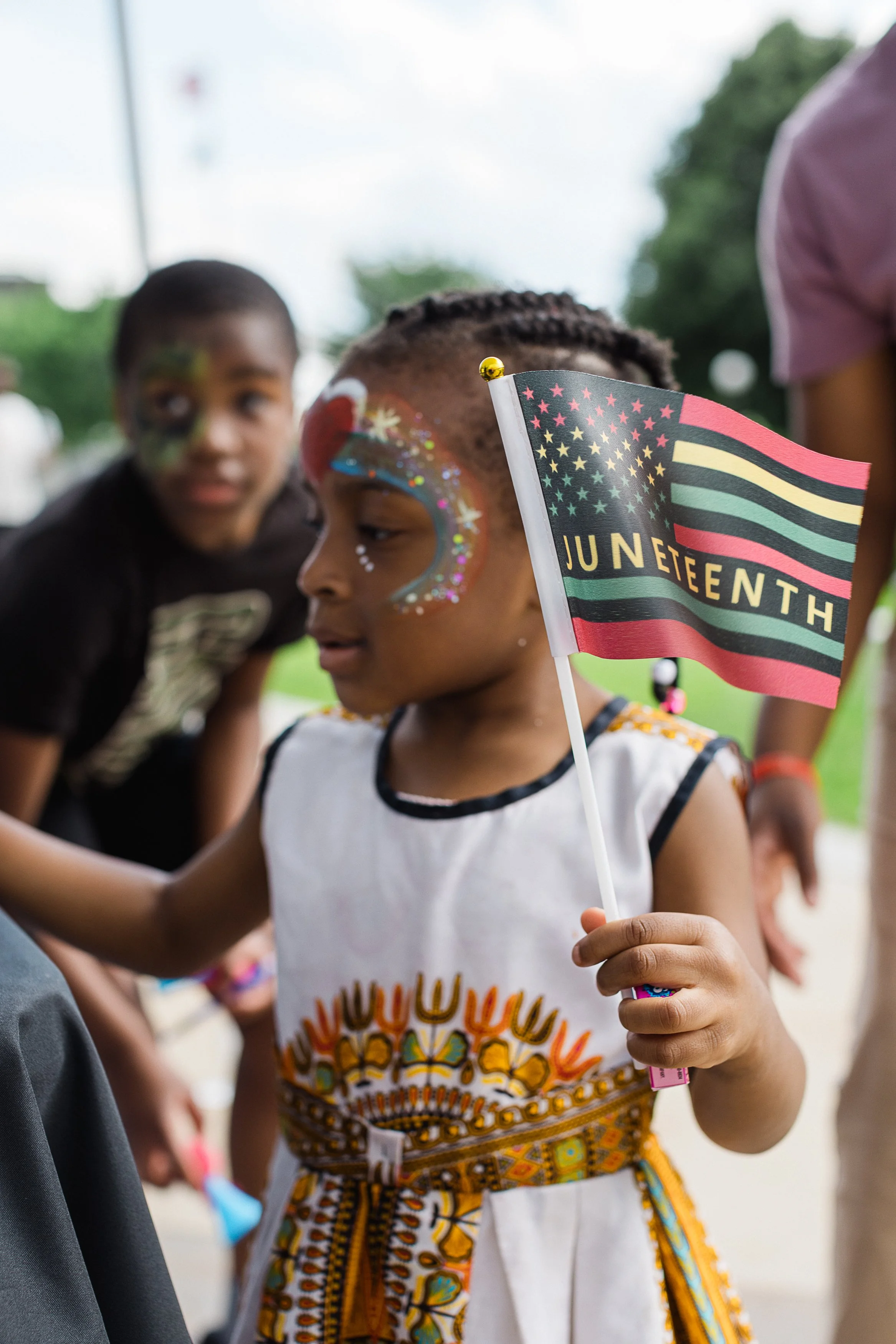 A young girl holding a small American flag with 