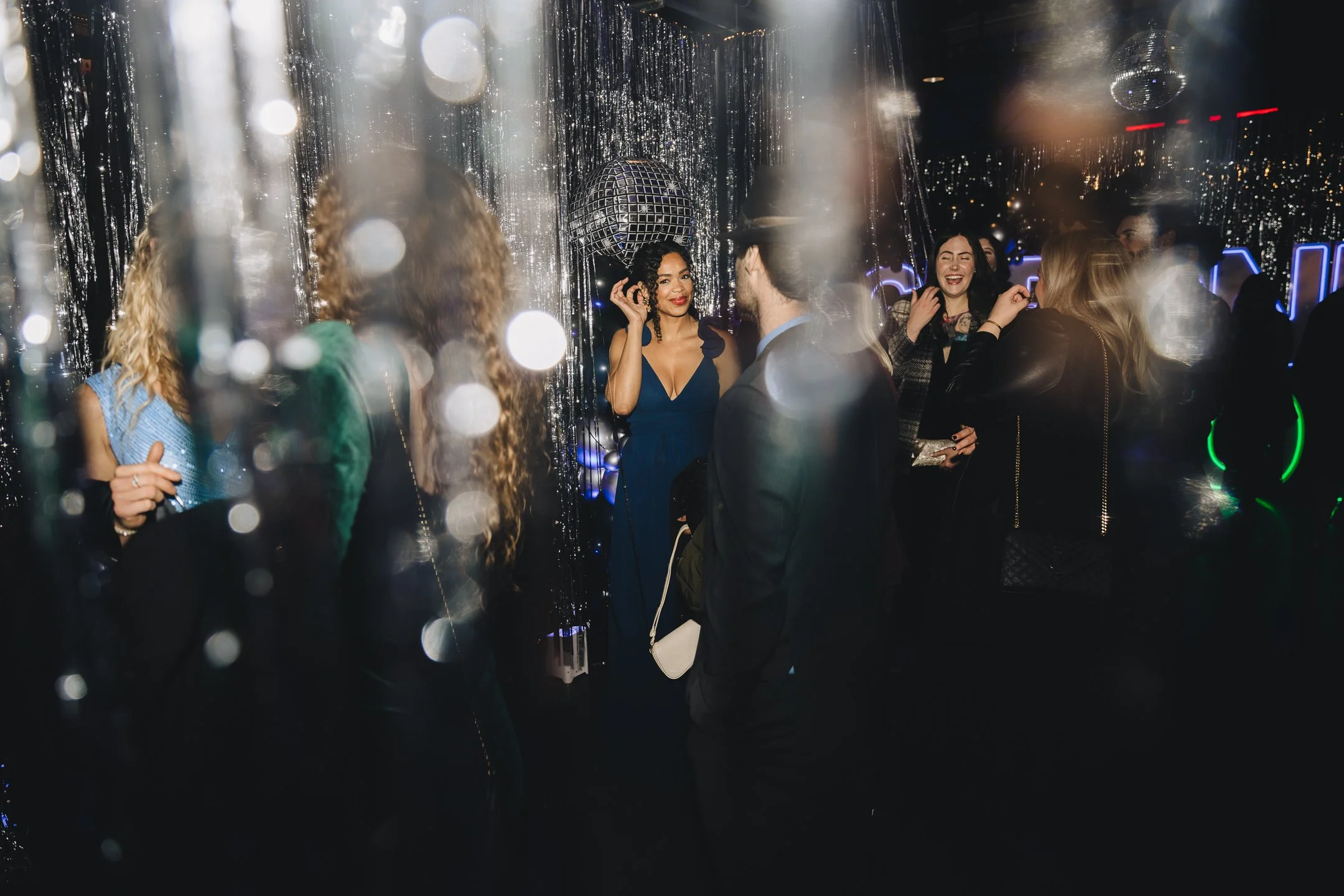 Group of people dancing and socializing at a nightclub with disco balls and lighting effects.