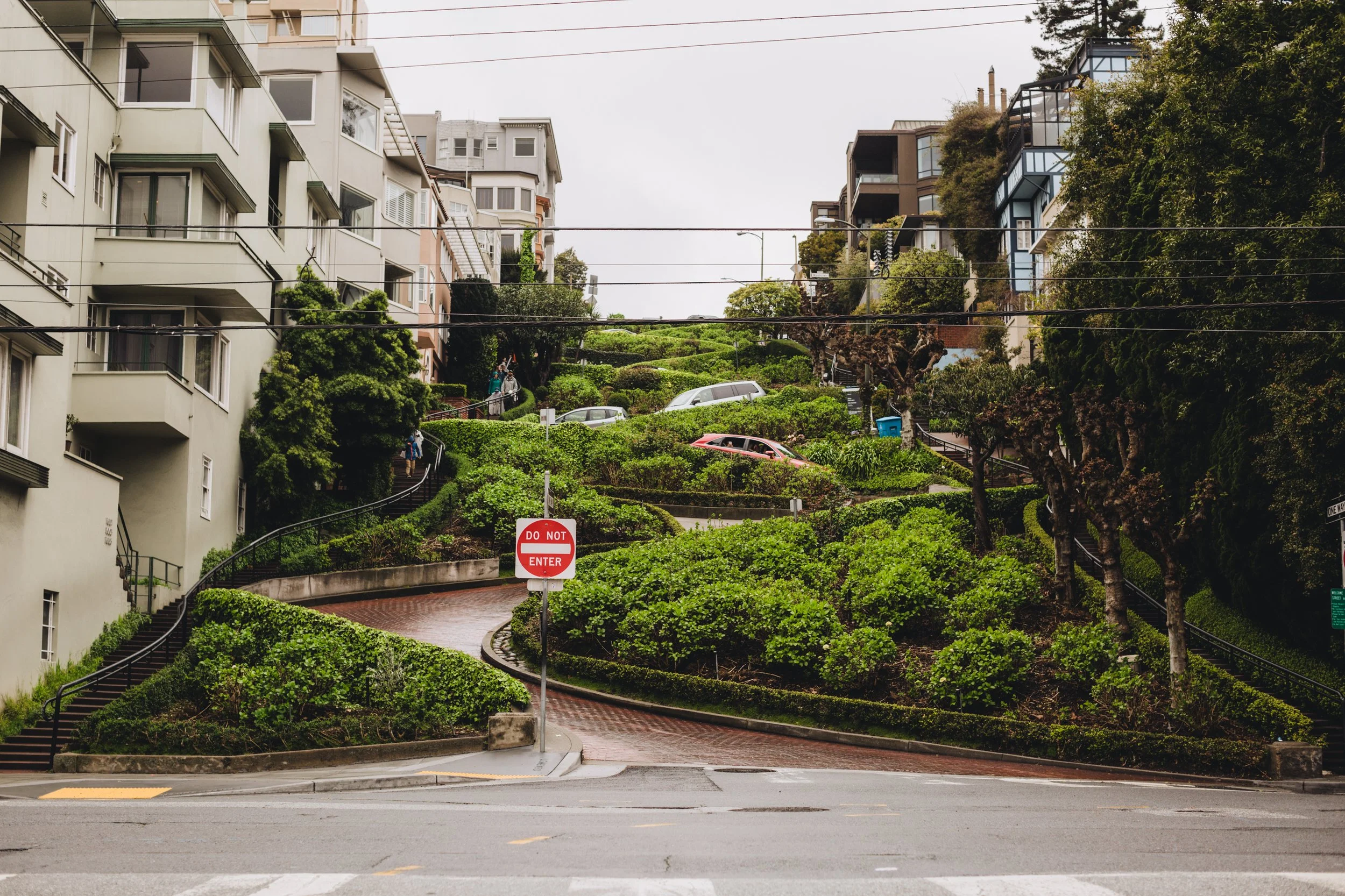 Steep streets with greenery, parked cars, residential buildings, and a 'Do Not Enter' sign at the bottom of the hill.